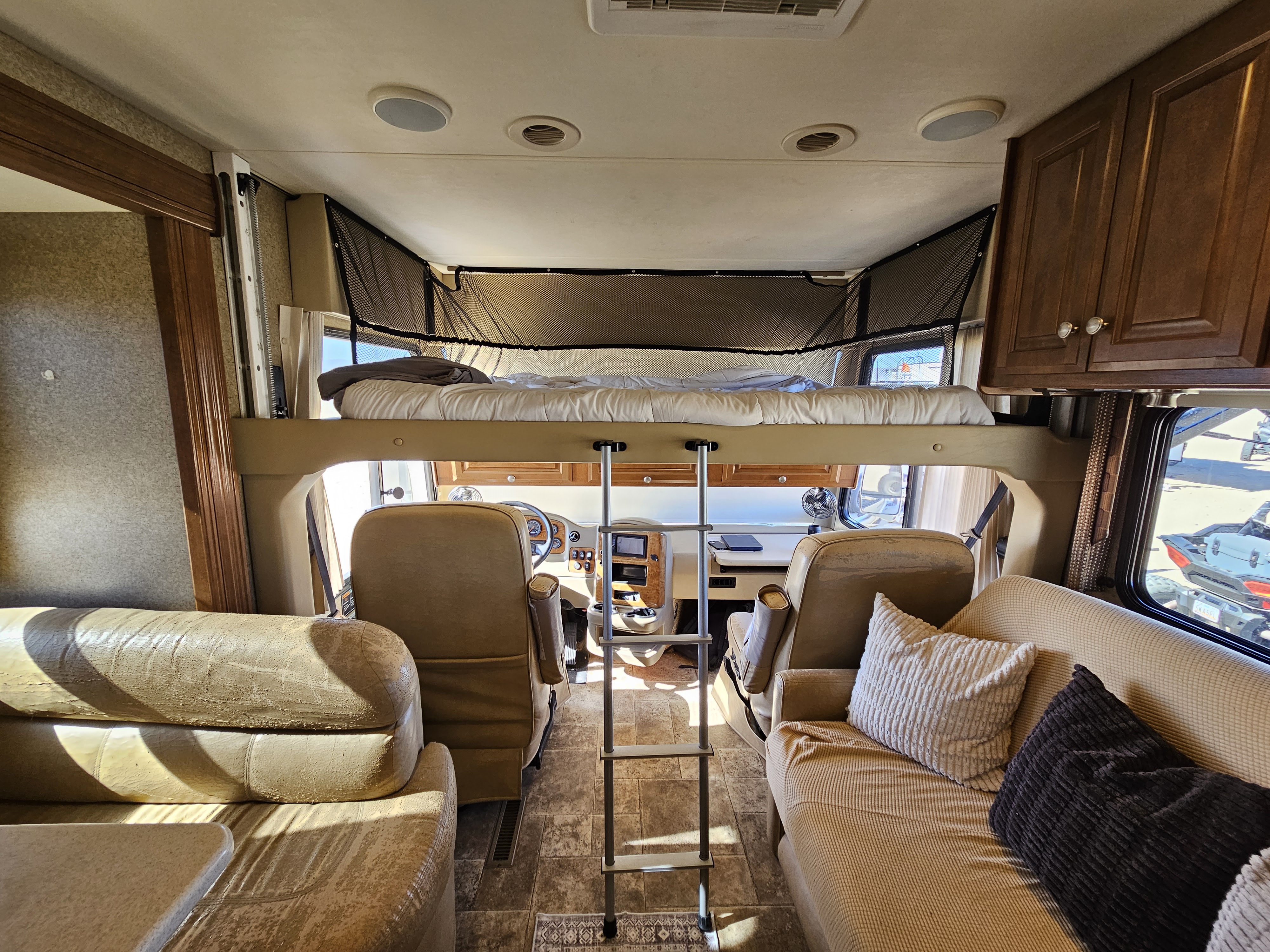 Spacious RV rental interior featuring an overhead bunk bed, front cockpit, and comfortable living areas. Perfect for adventures!. Thor Palazzo 2013