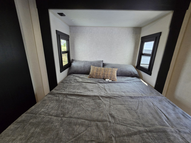 Cozy RV rental bedroom with a comfortable bed, grey textured bedding, and two side windows with black frames.. Forest River Hemisphere 2025