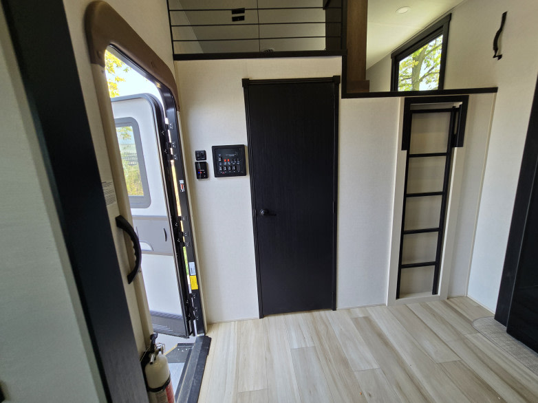 Inside a sleek RV rental: open entrance, control panel, and ladder to a cozy loft area with a window.. Forest River Hemisphere 2025