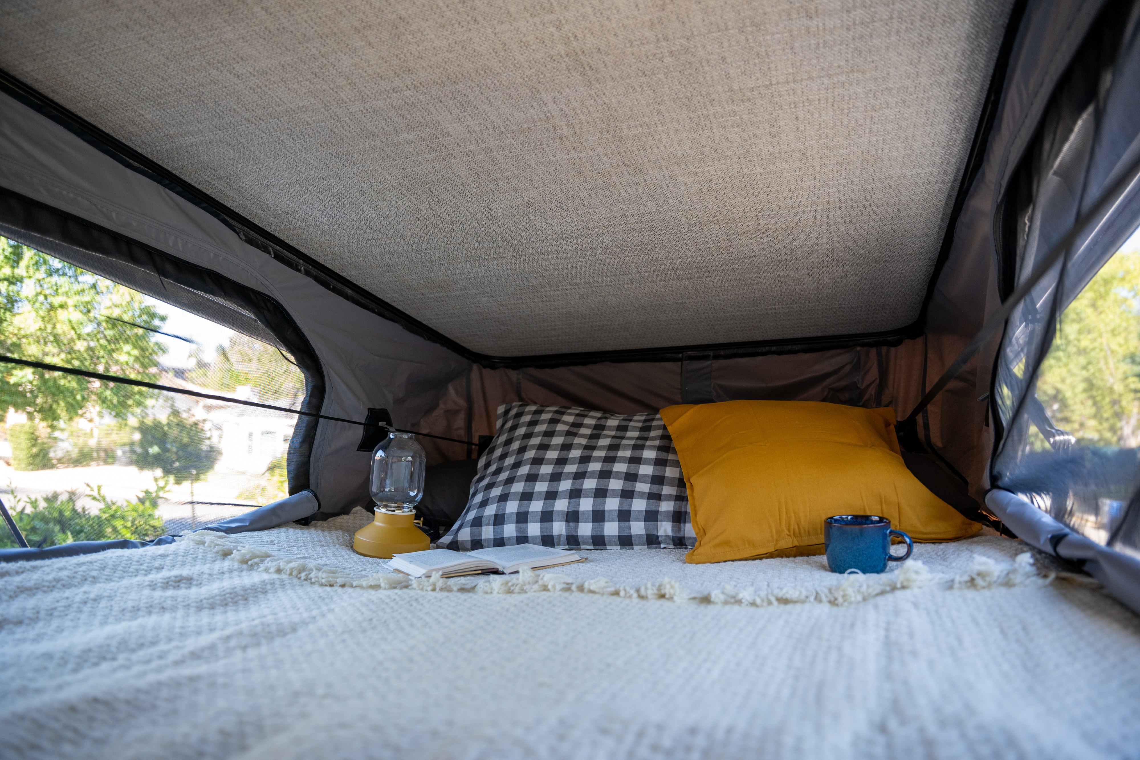 Cozy RV rental interior with comfy bed, pillows, book, and lantern. Perfect for a comfortable glamping adventure.. Winnebago Solis 59px 2025