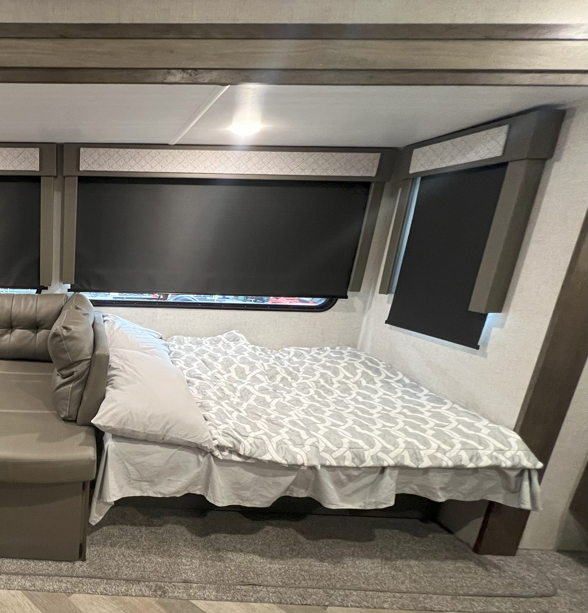 RV rental: Cozy interior features a bed with patterned bedding next to a sofa, dark window blinds, and overhead lighting.. Forest River Wildwood 2021