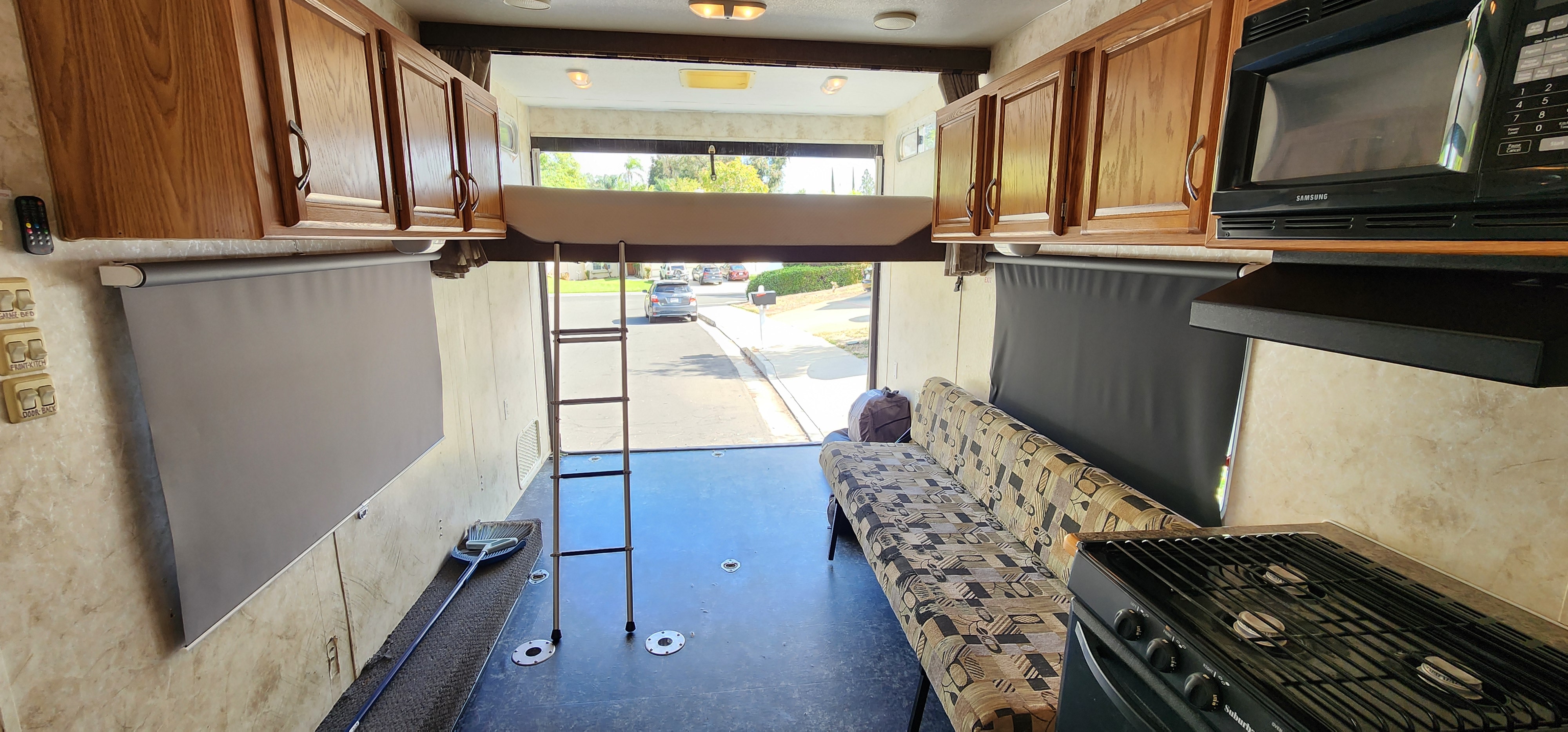 RV rental toy hauler interior with overhead bunk bed, kitchen, sofa, and open rear ramp view of street.. Eclipse Recreational Vehicles Attitude 2025