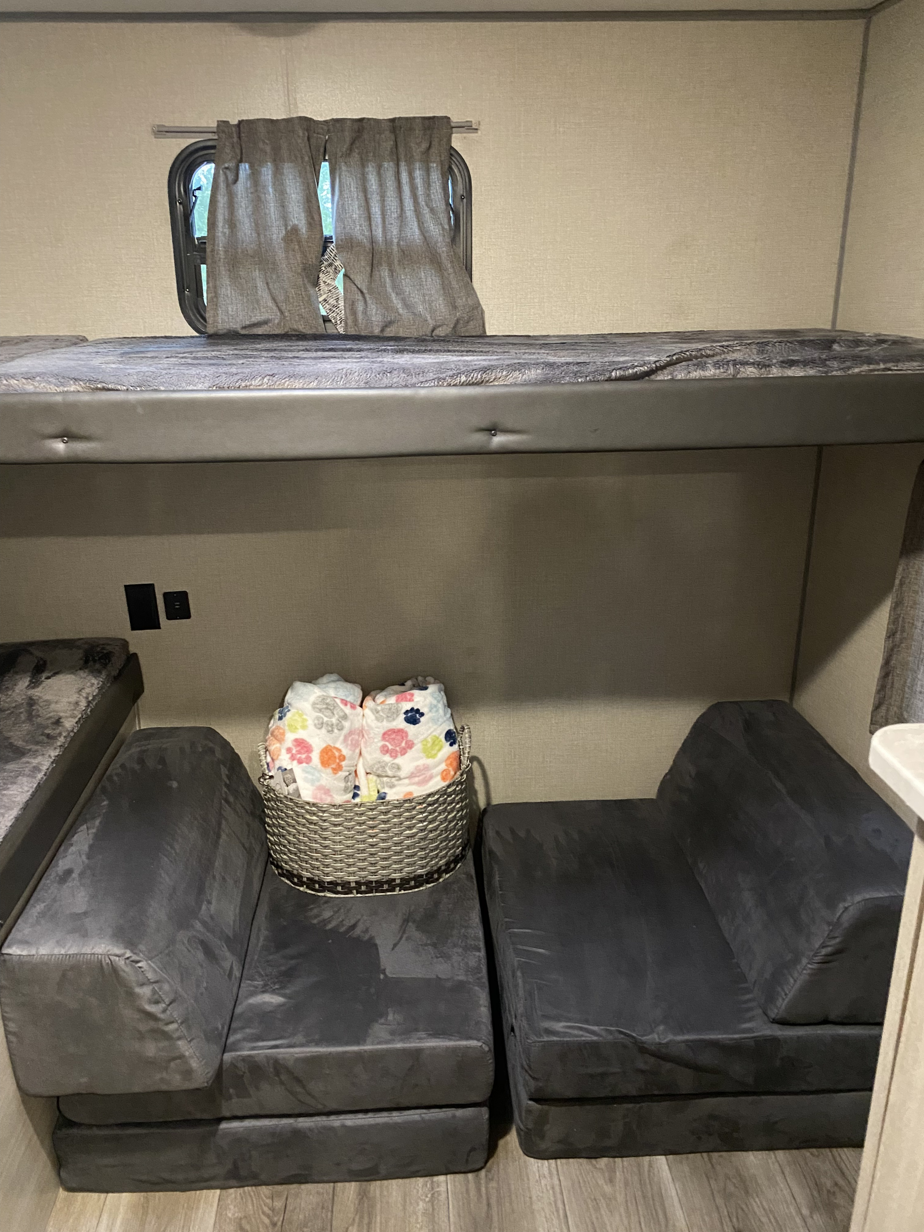 RV rental interior featuring a bunk bed, two modular foam seats, power outlets, and a basket of paw-print blankets.. Forest River Coachmen Catalina Legacy 2022