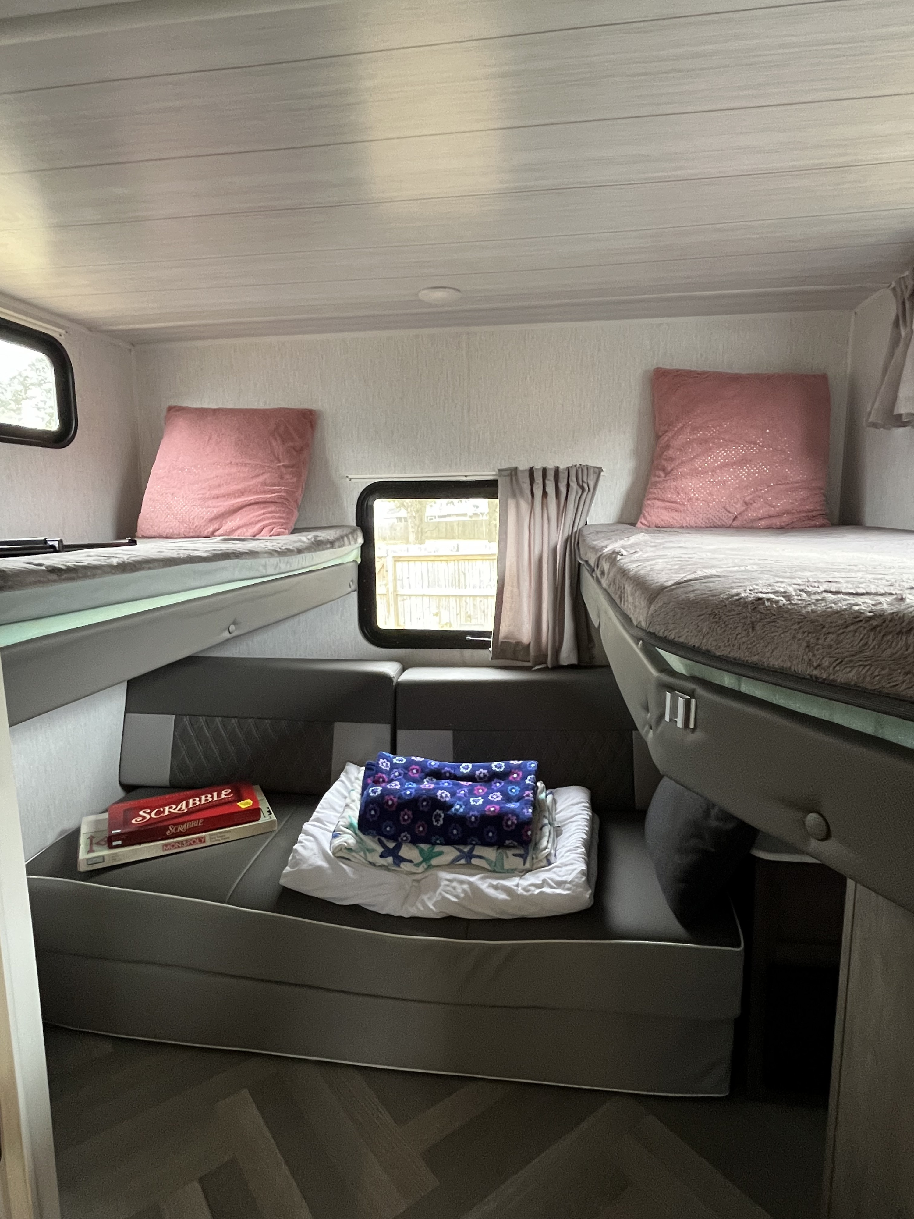 Cozy RV rental interior: bunk beds, a central dinette with board games and blankets. Ideal for family camping.. Forest River Wildwood X-Lite 2022