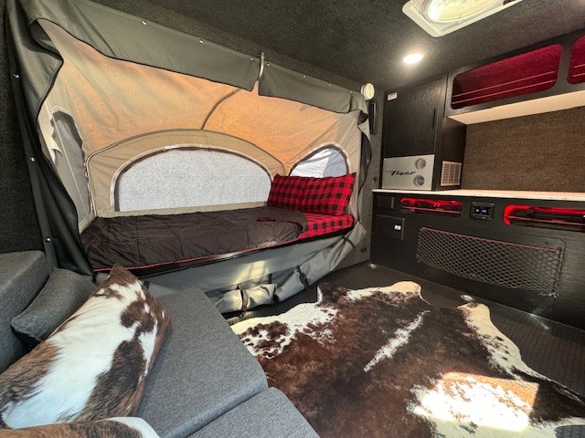 Cozy RV rental interior with pop-out bed, modern kitchenette, and stylish cowhide rug. Ready for adventure!. InTech RV Flyer 2023