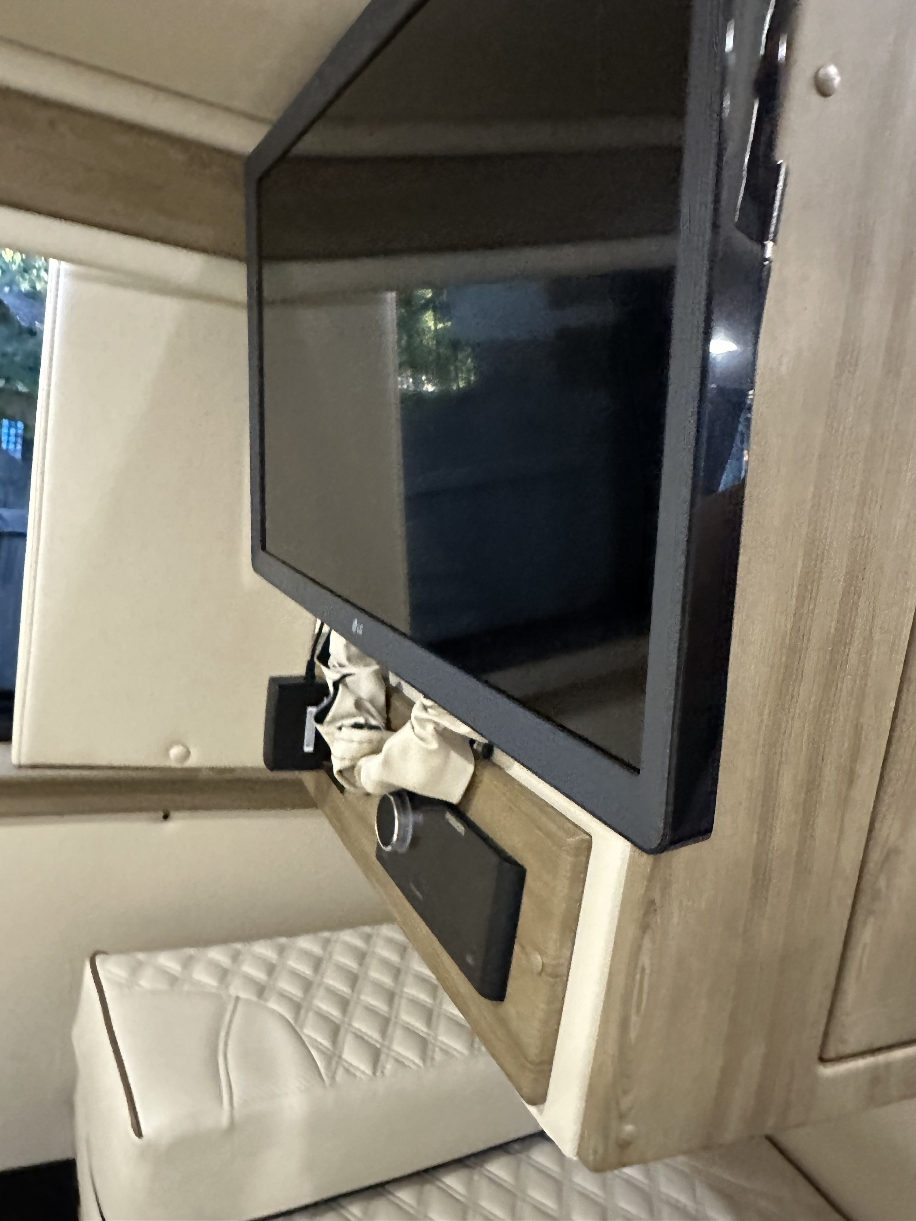 An RV rental interior features a mounted LG TV, speaker, and quilted seating. A cozy entertainment setup for your travels.. Midwest Automotive Designs Midwest Automotive Designs Class B 2022