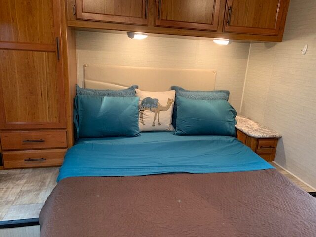 Cozy RV rental bedroom with a comfy bed, blue bedding, and storage. Perfect for your travel accommodations.. Jayco Redhawk 2017