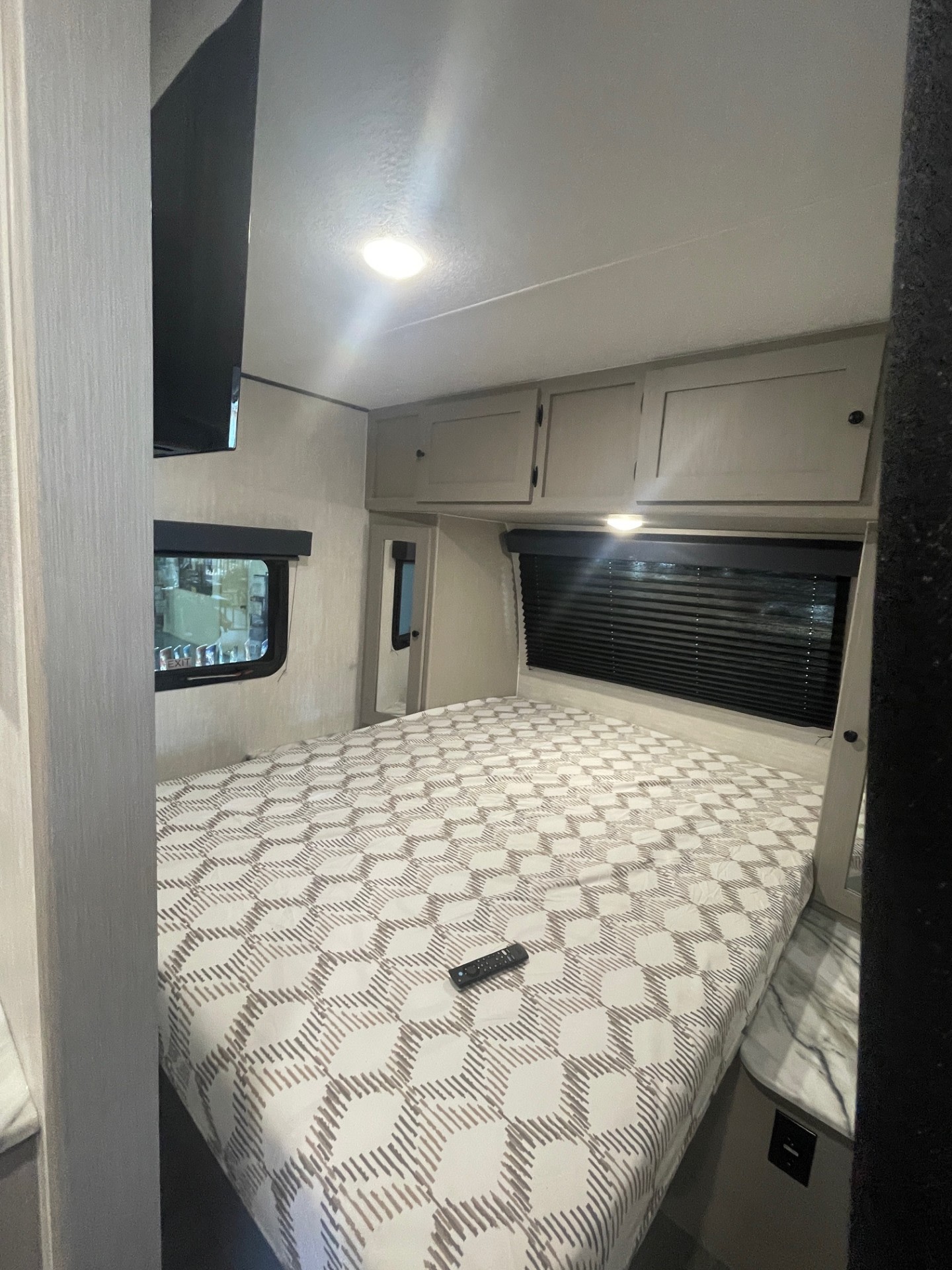 Cozy RV rental bedroom featuring a patterned bed, wall-mounted TV, and practical storage. Perfect for a comfortable journey.. Coachmen Apex 245 BHS 2025