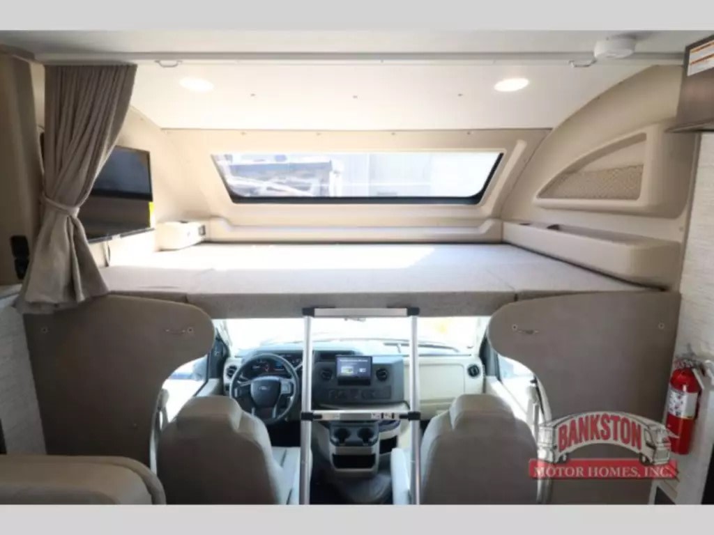 Inside an RV rental: a large cab-over bunk extends over the driver's cockpit, complete with a TV. Ready for travel adventures.. Entegra Coach Odyssey 2024