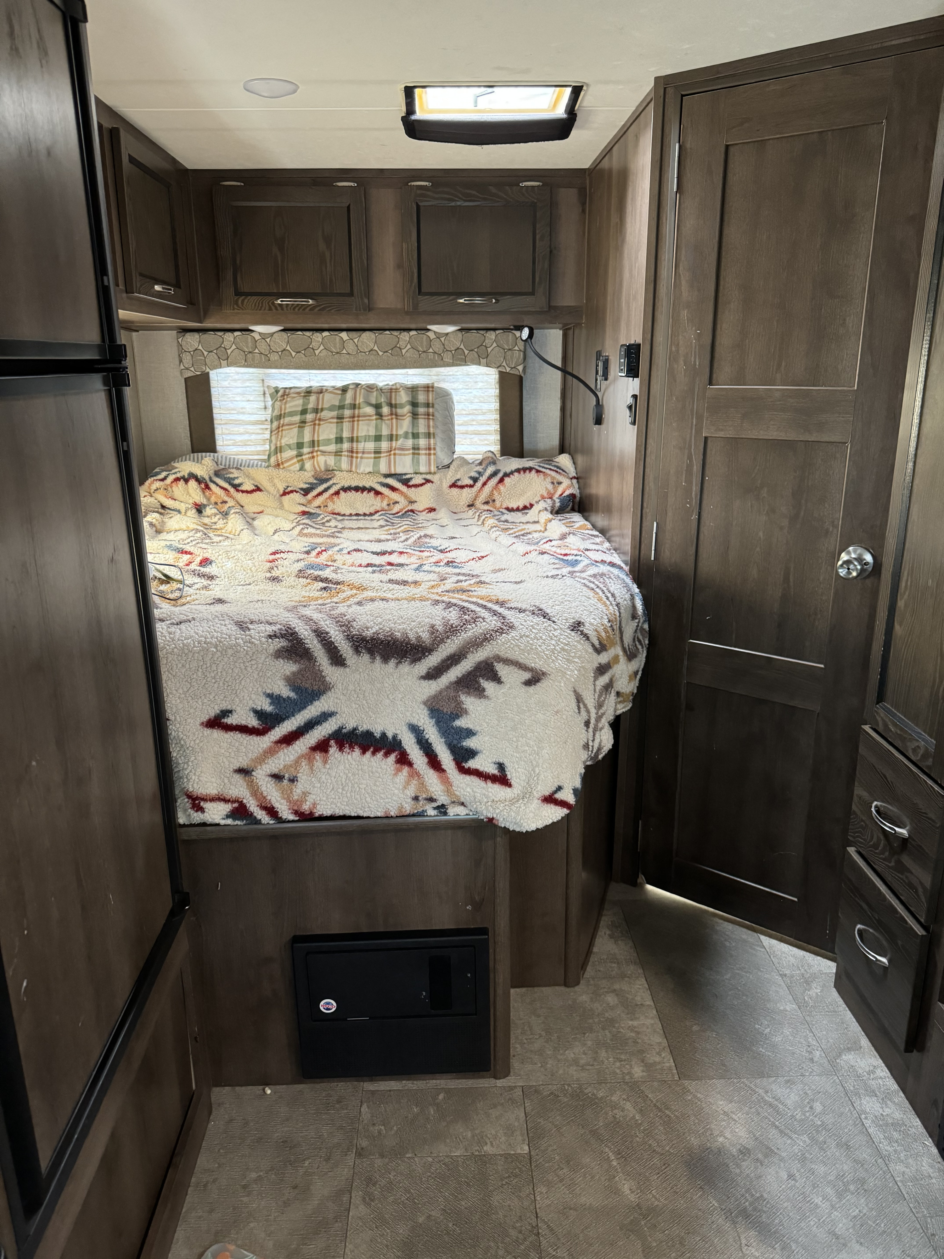 An inviting RV rental bedroom with a cozy bed, patterned blanket, overhead storage, and compact layout.. Coachman Freelander 2019