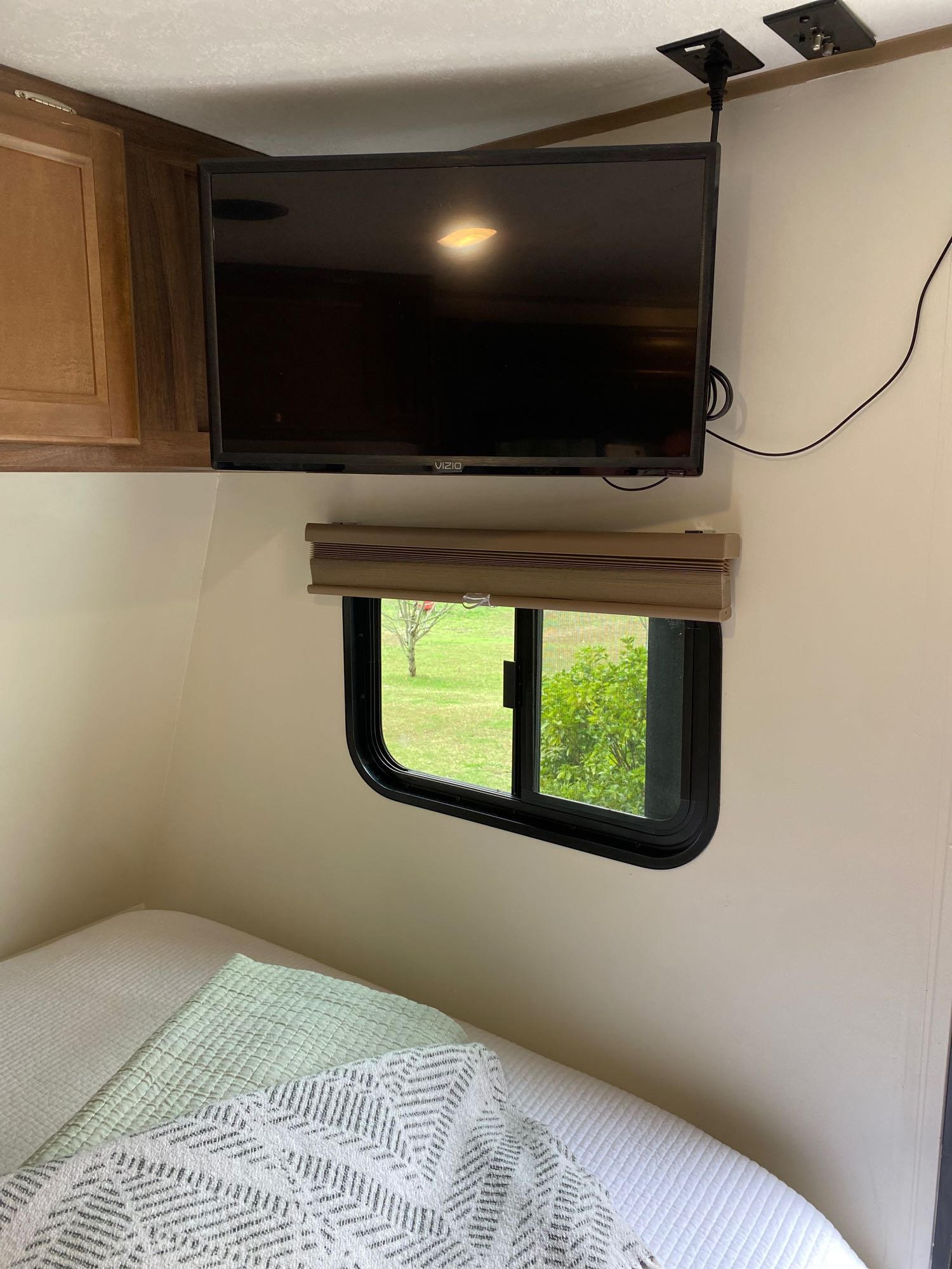 Cozy RV rental interior featuring a ceiling-mounted TV, a window with green outdoor views, and a comfortable bed.. Clipper Clipper Trailer 2018