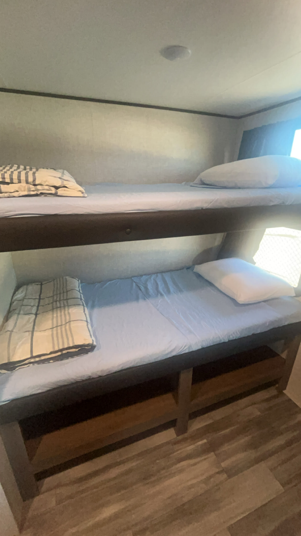 Inside an RV rental: two cozy bunk beds with light blue sheets and a window for natural light. Ideal for family travel.. Jayco Jay Flight 2024