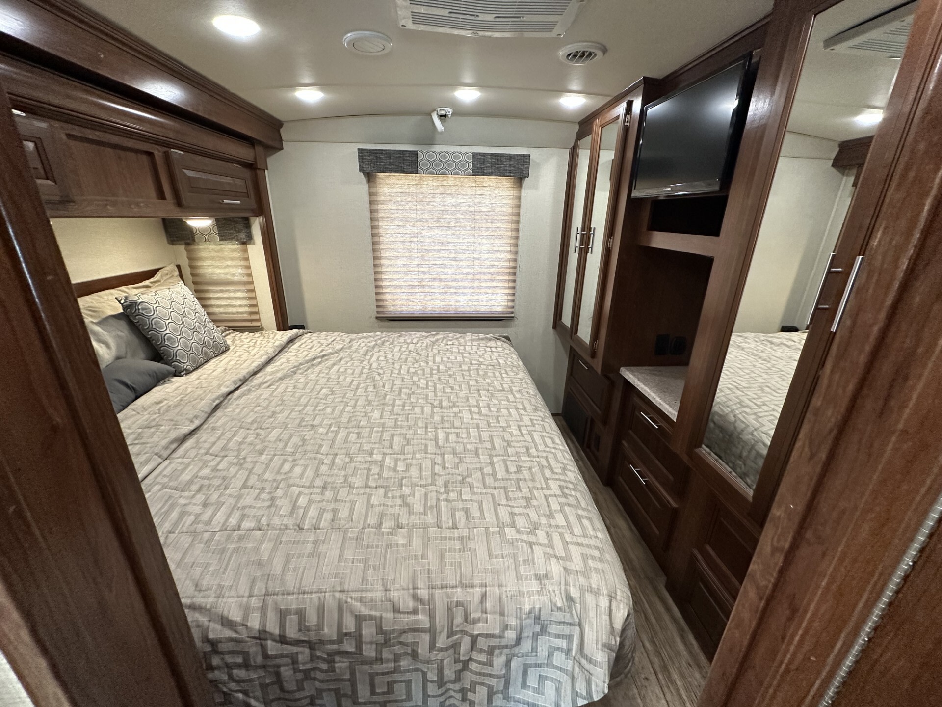 Modern RV rental bedroom interior: large bed, dark wood cabinetry, TV, and window. Ample storage for comfortable travel.. Forest River Fr3 2019
