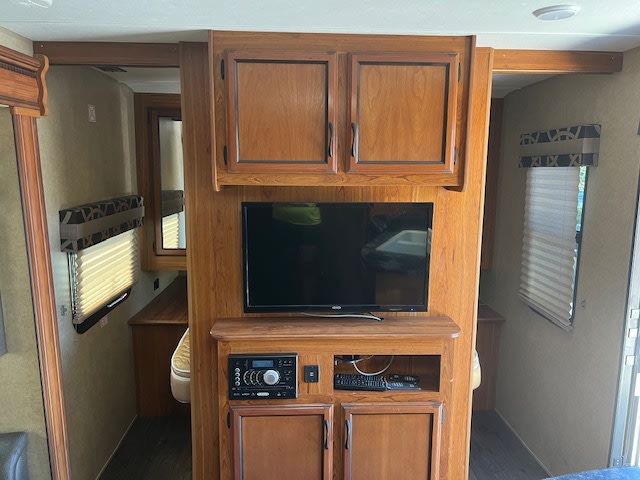 Inside a comfortable RV rental: Central wooden entertainment unit with a TV and stereo, flanked by open doorways.. Starcraft Autumn Ridge 2016