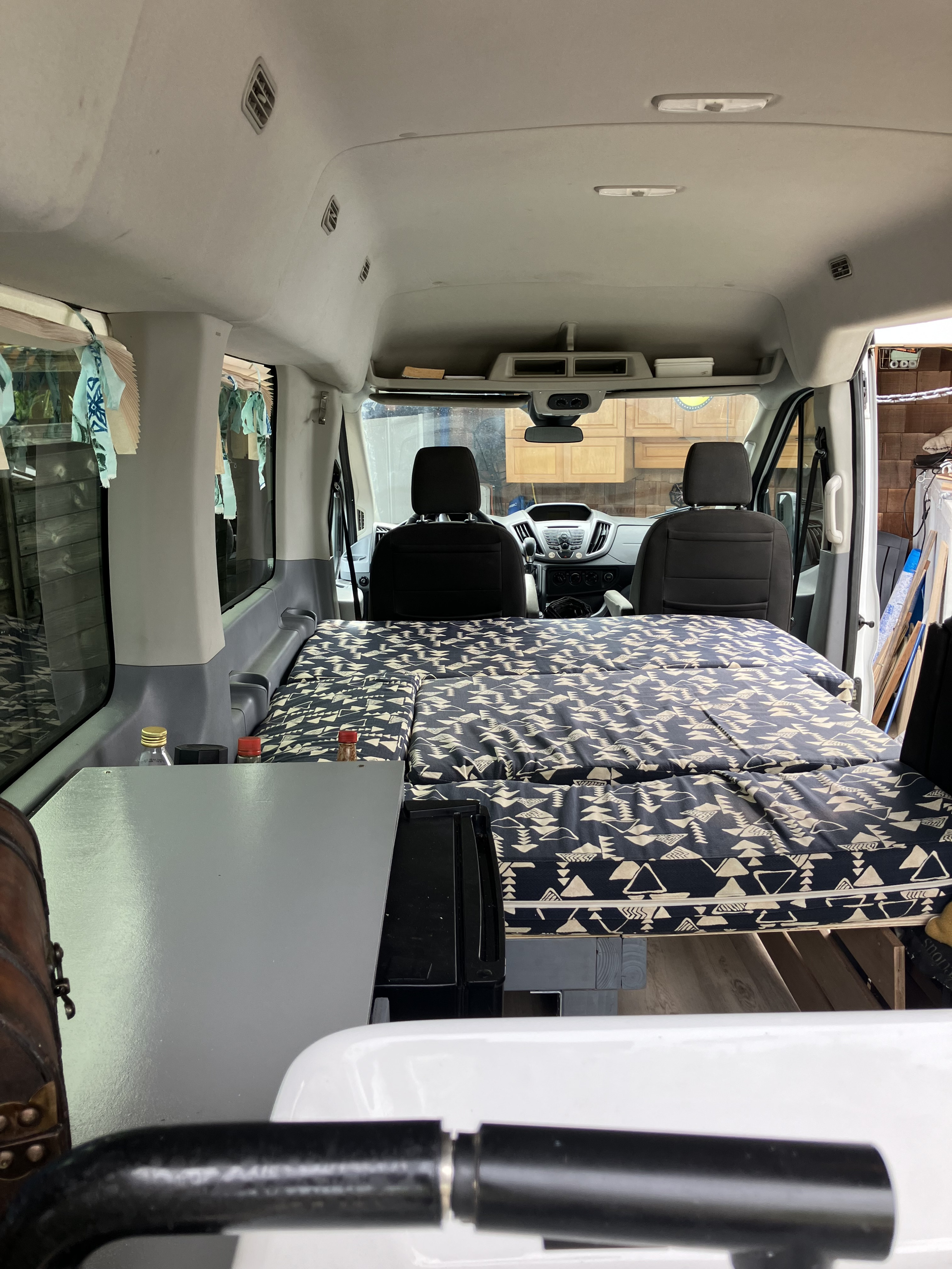 Cozy camper van interior with a patterned bed, ideal for an rv rental adventure. View from rear to front seats.. Ford Transit 2018