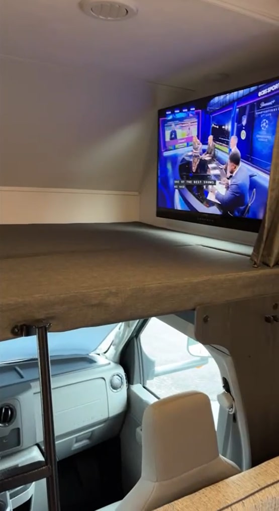 An rv rental's cozy interior features a cab-over bunk bed with a mounted TV, perfect for entertainment and relaxation.. Forest River Solera 2023
