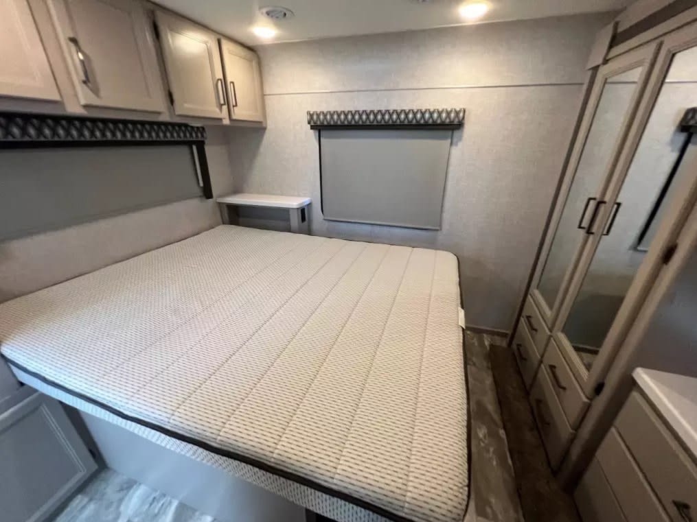 Cozy RV rental bedroom with spacious bed, overhead cabinets, and built-in wardrobe for a comfortable stay.. Thor Motor Coach Quantum LF31 2023