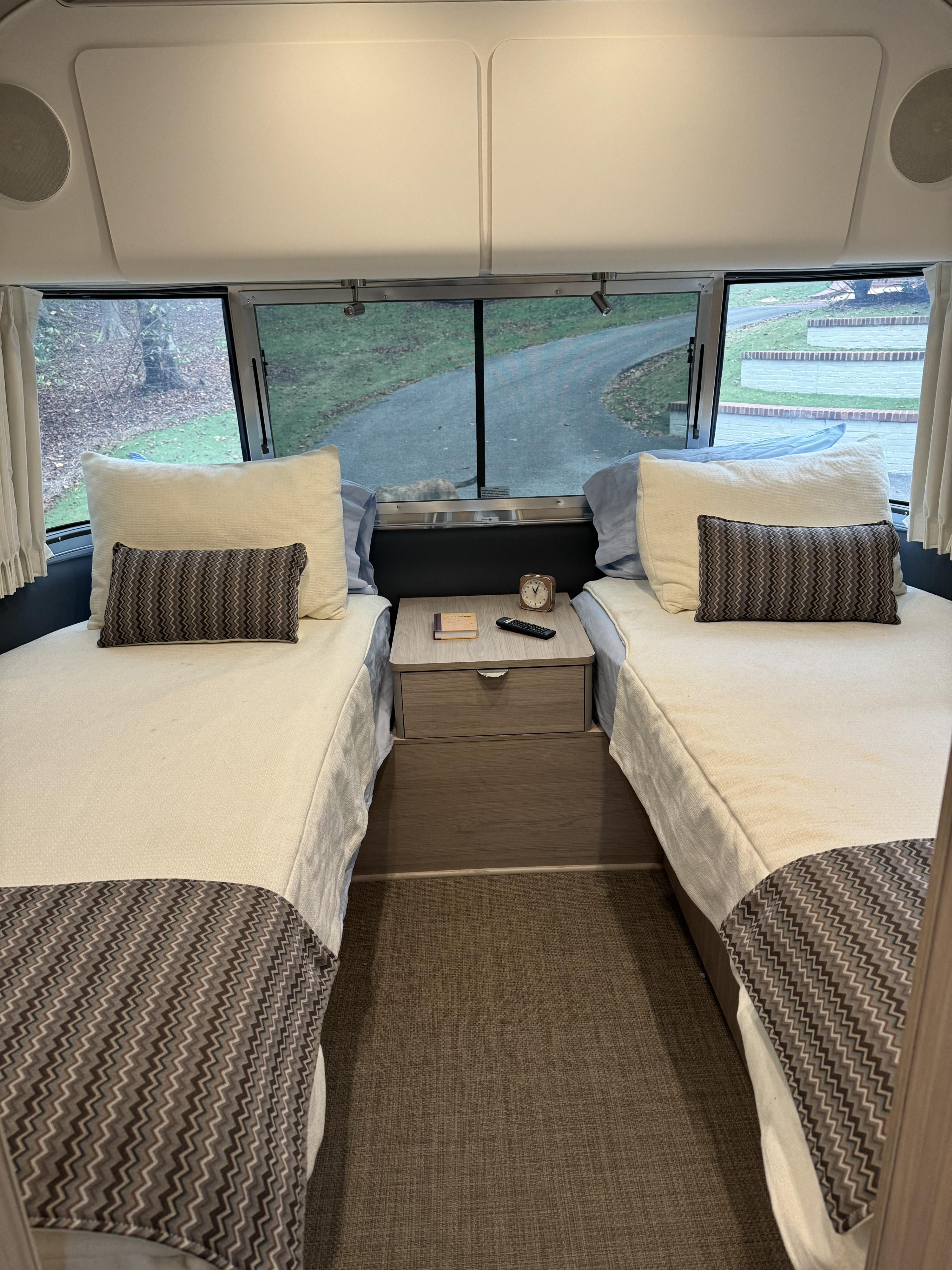 Cozy RV rental bedroom featuring twin beds, a nightstand, and large windows for scenic views.. Airstream Globetrotter 2024