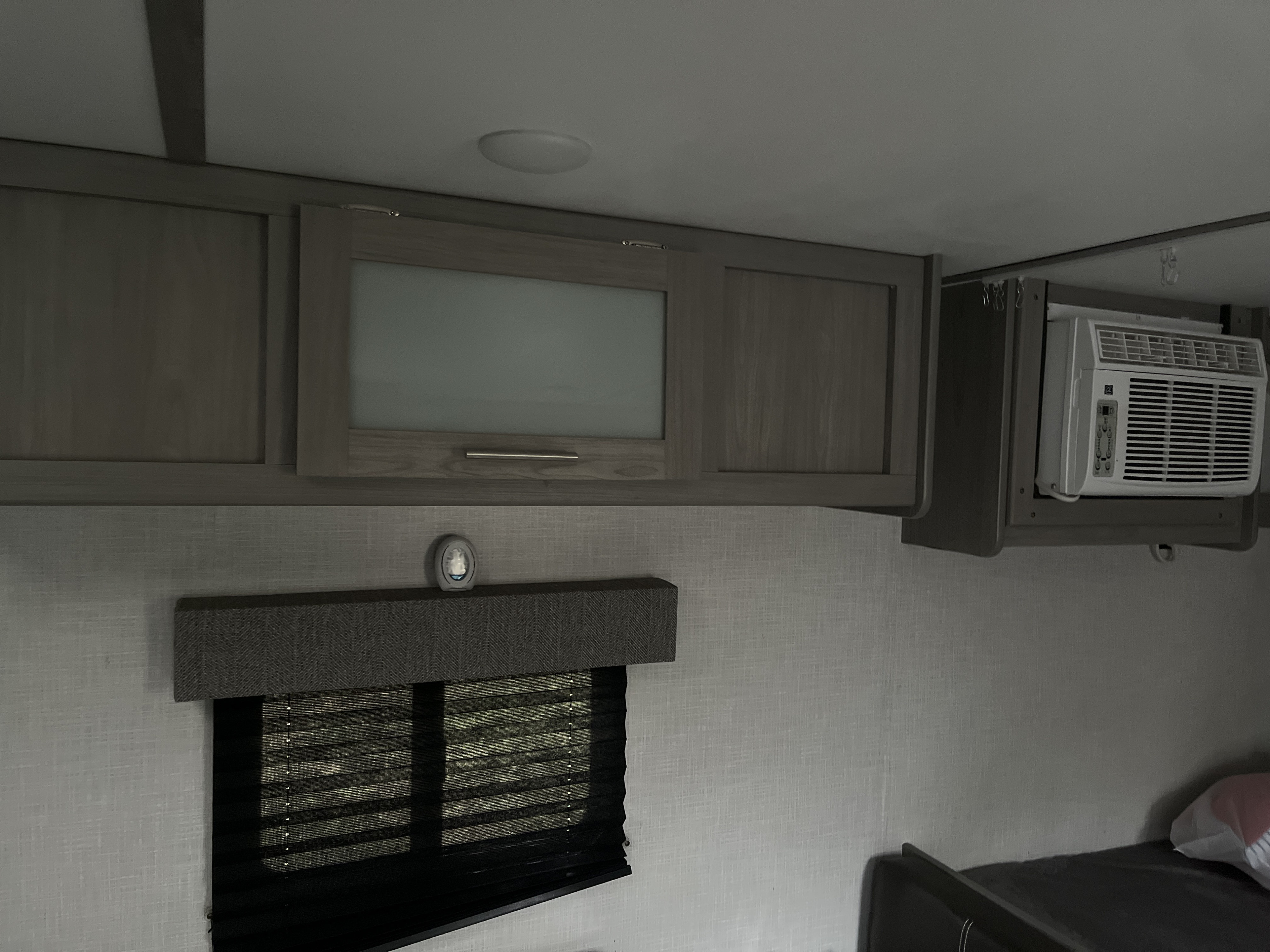 Comfortable RV rental interior featuring overhead storage, a compact AC unit, window with blind, and a visible bunk bed.. Coleman Lantern 17b 2022