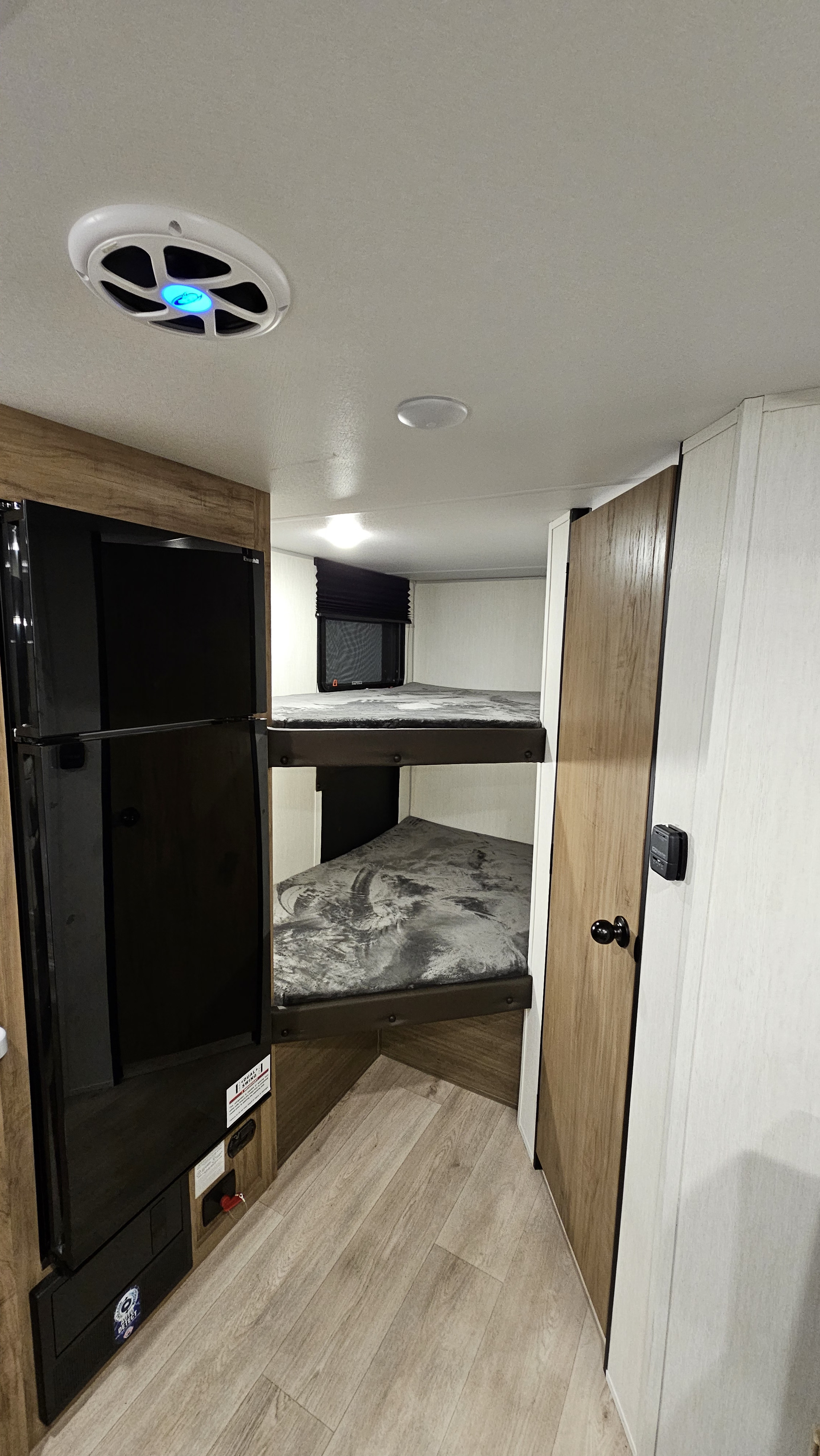 Cozy RV rental interior: bunk beds, refrigerator (left), and control panel visible. Compact living for your travels.. Forest River 17JW 2025