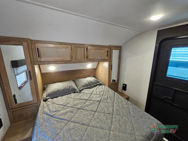RV bedroom interior features a comfy bed with grey bedding, overhead cabinets, and mirrors. Book your RV rental getaway!. Forest River Cherokee 2023