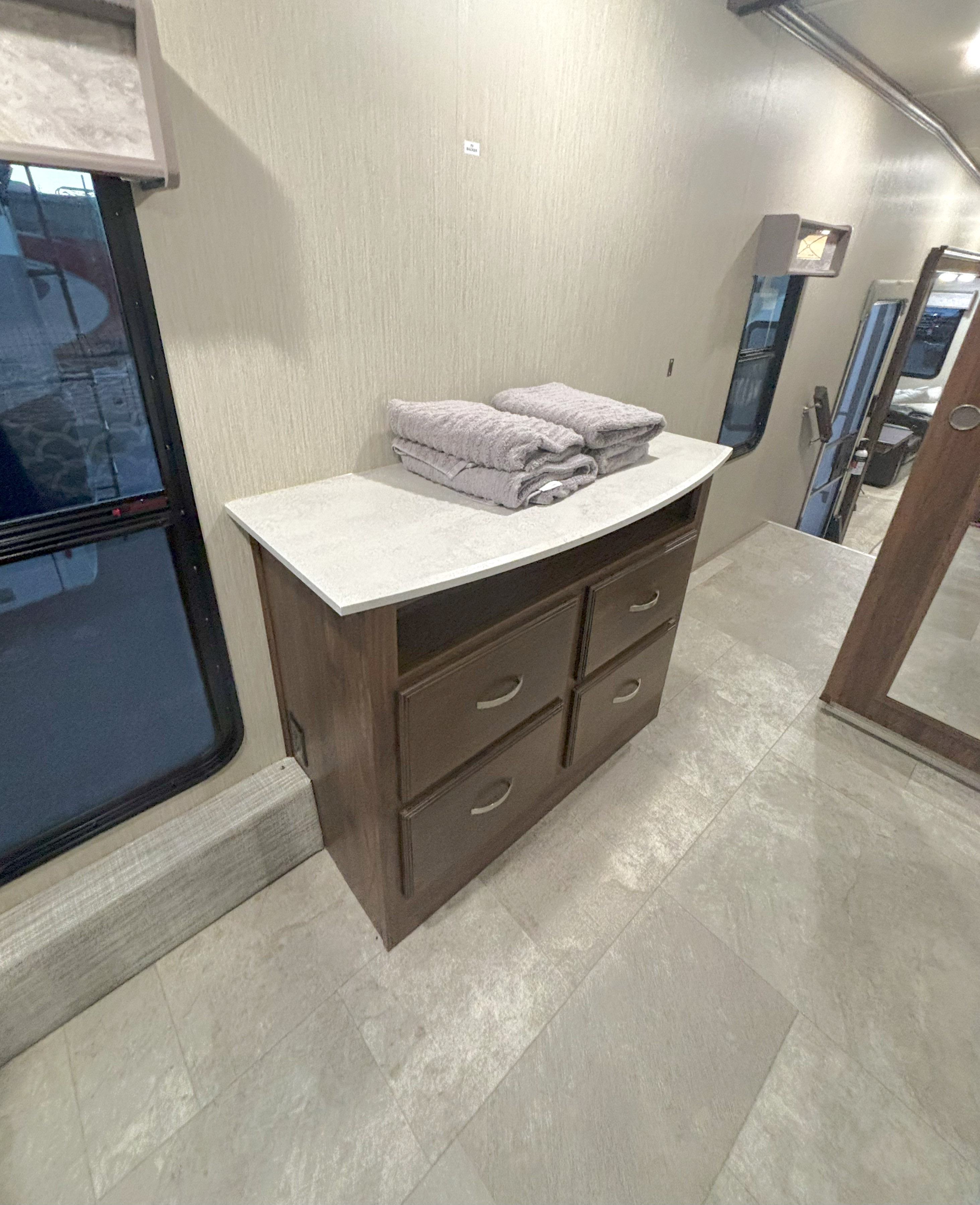 RV rental interior: light-colored dresser with four drawers and fresh towels, beside a large window. Practical camper storage.. Palomino Columbus 2021