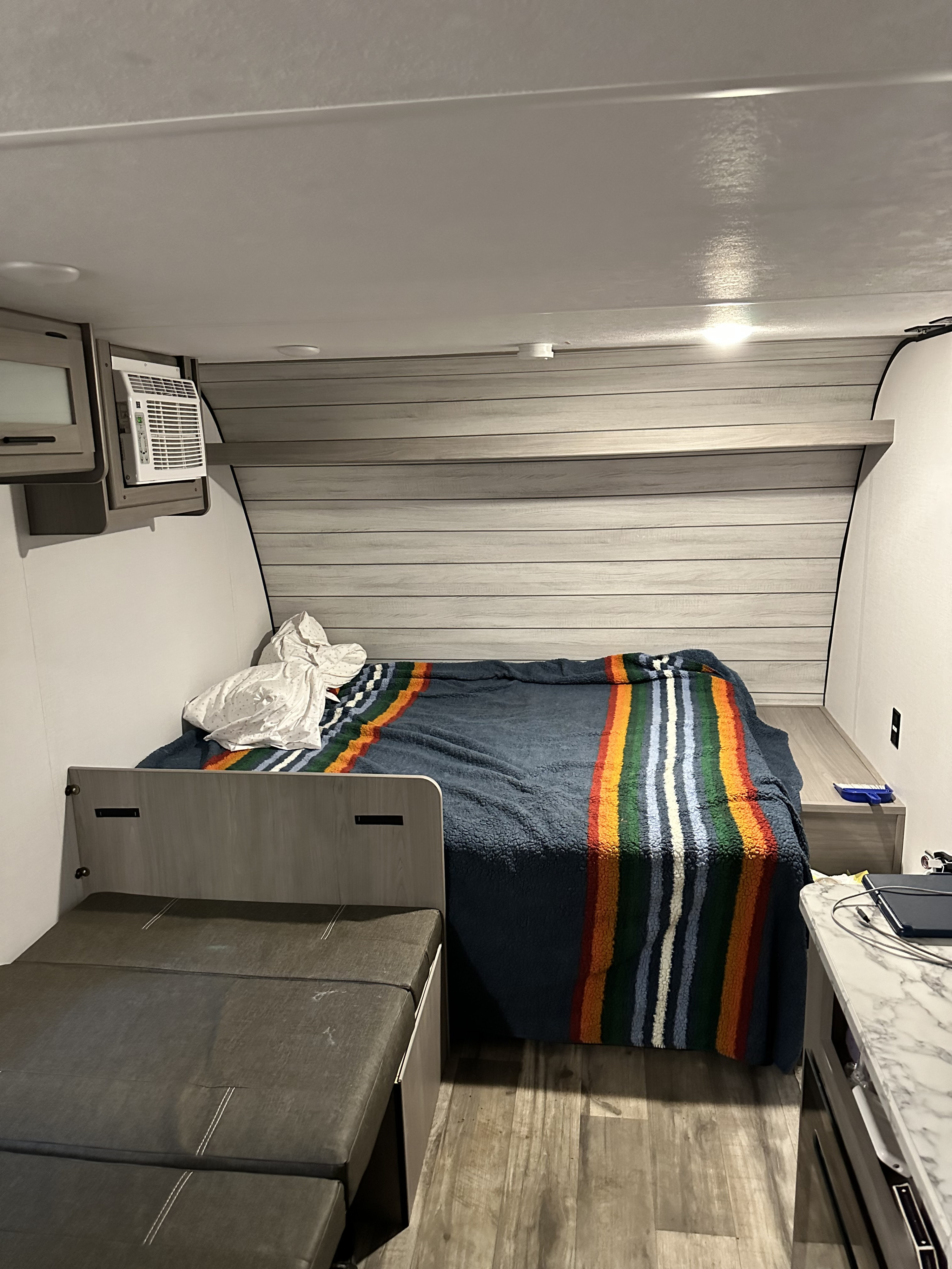 Inside a compact RV rental, featuring a comfortable bed with a vibrant blanket, an AC unit, and flexible seating.. Coleman Coleman lantern 17b 2024
