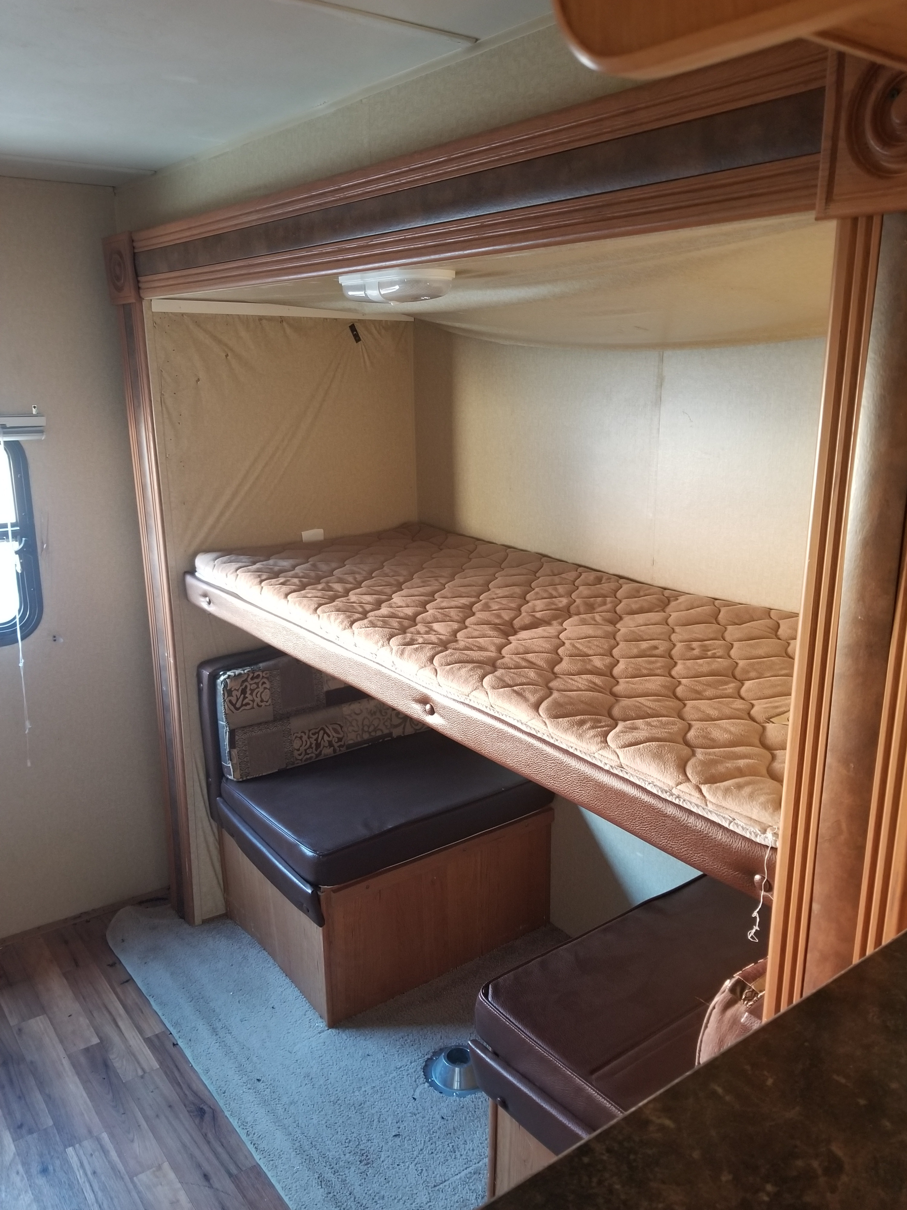 RV rental interior: a comfy bunk bed with quilted mattress sits above a brown leatherette dinette area.. Forest River Salem 2012