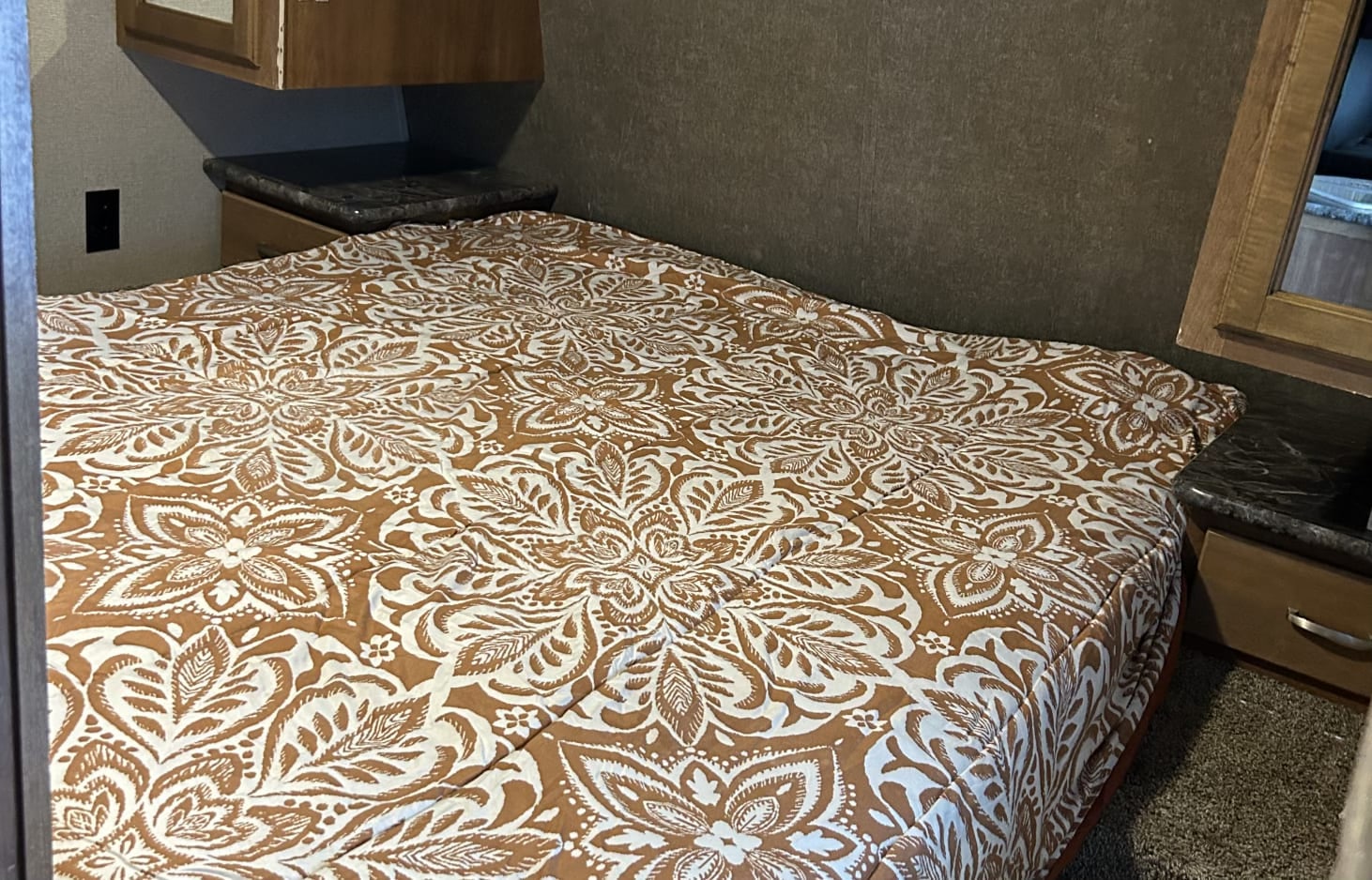 Cozy rv rental bedroom with a detailed brown and white floral patterned comforter and built-in nightstands.. Keystone RV Springdale 2018
