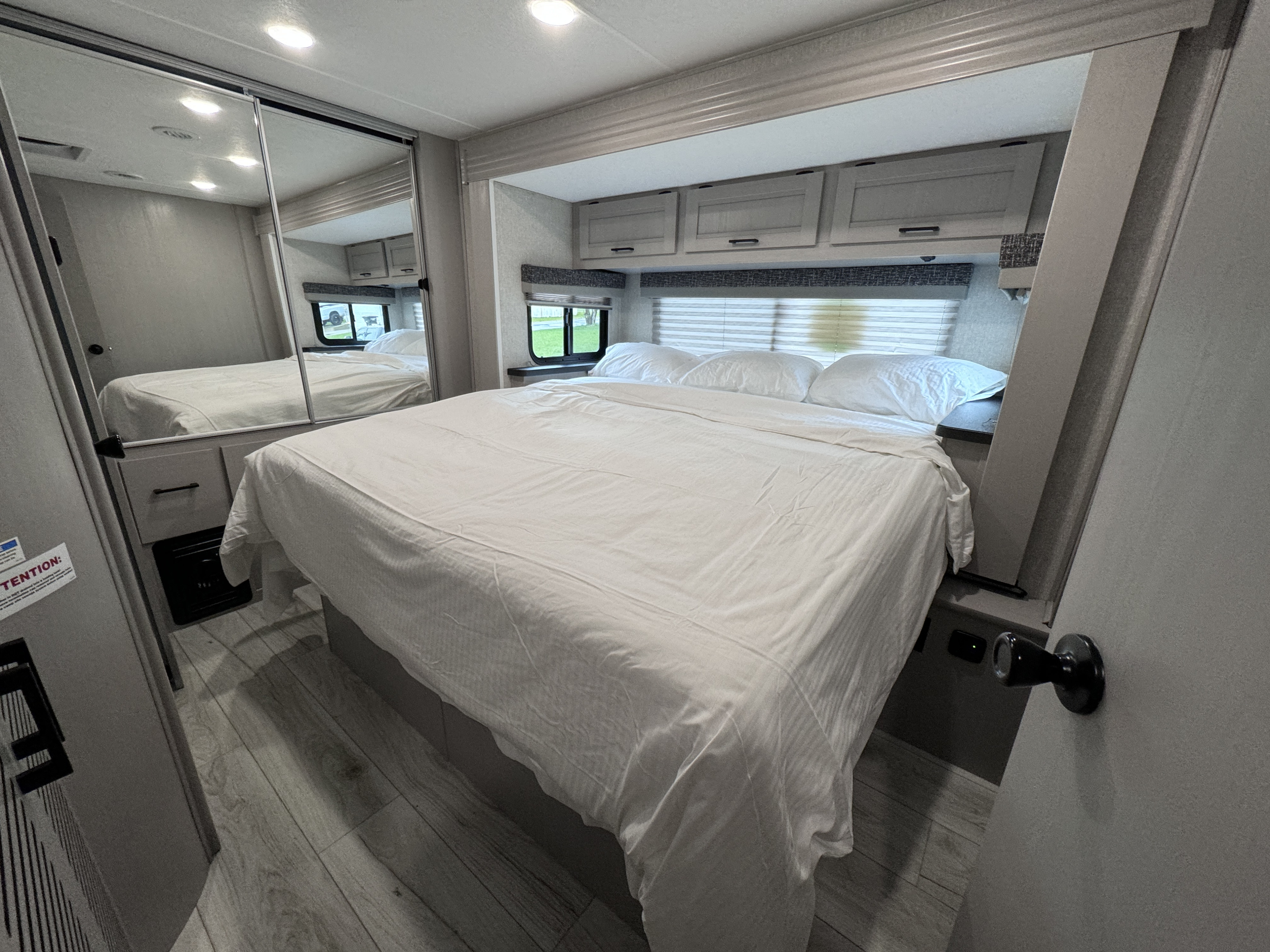 Cozy RV rental bedroom featuring a comfy bed, mirrored closet, overhead storage, and light, modern interior.. Forest River Coachmen Freelander 2026