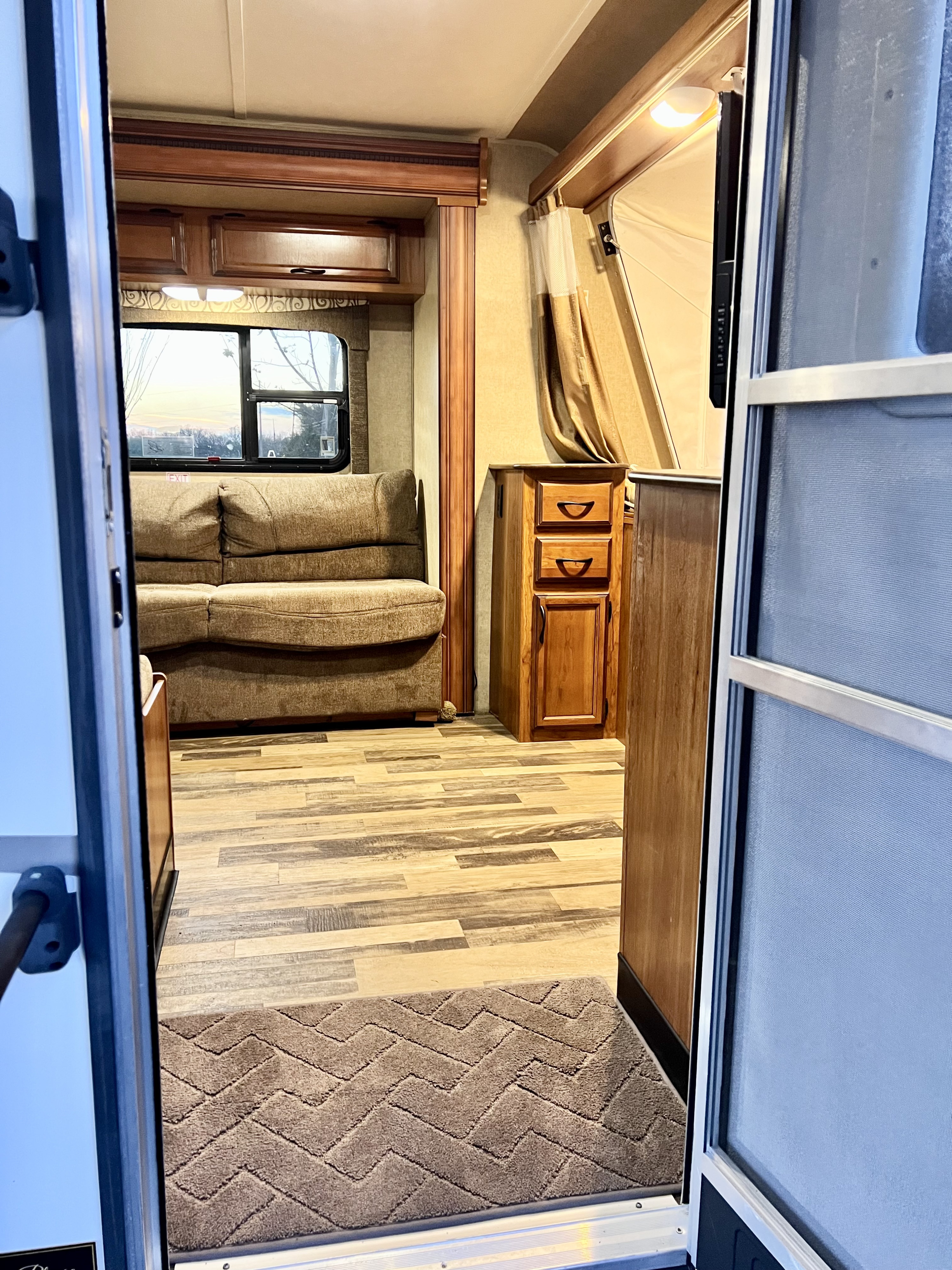 Cozy RV rental interior with a brown sofa, wood-look floors, and cabinets, viewed from the open doorway.. Starcraft Travel Star 2015