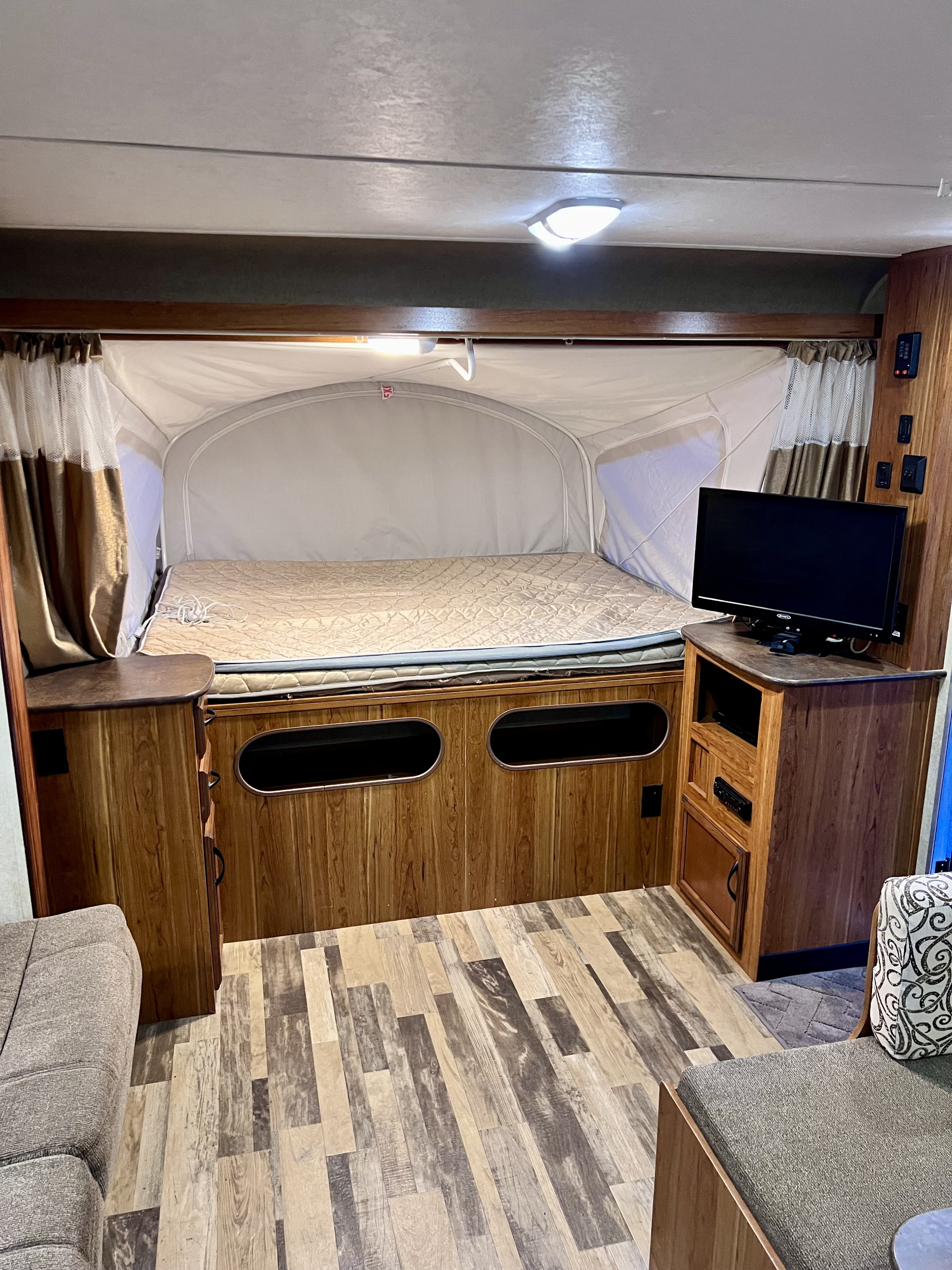 Cozy RV rental interior featuring a comfortable bed, entertainment area with TV, and modern wood finishes.. Starcraft Travel Star 2015
