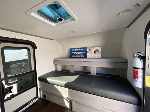 Cozy RV rental interior showing bunk beds, an exit door, a ceiling vent, and a fire extinguisher.. Dutchmen Coleman Rubicon 1400BH 2024