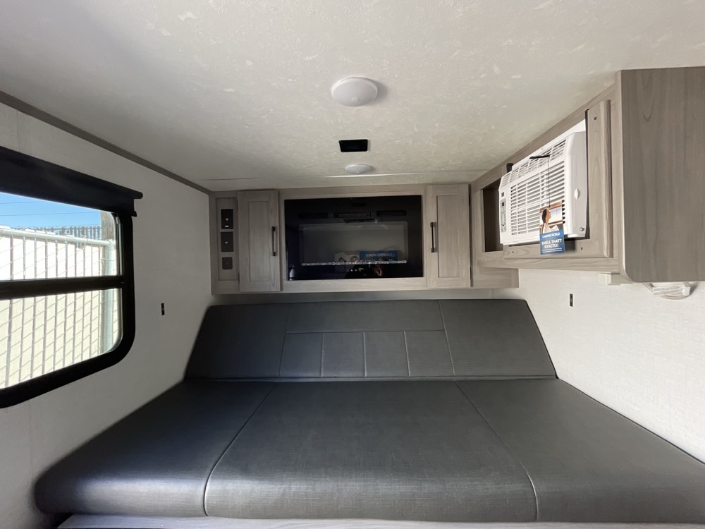 RV rental interior: a versatile bed/sofa, overhead cabinets, microwave, AC, and window create a functional living space.. Dutchmen Coleman Rubicon 1400BH 2024