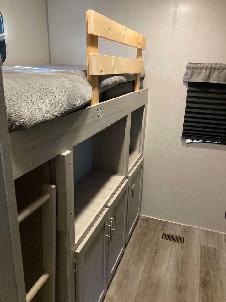 This RV rental features a cozy bunk bed with a wooden safety rail, built-in storage cabinets, and a ladder for easy access.. Coachmen Catalina 2022