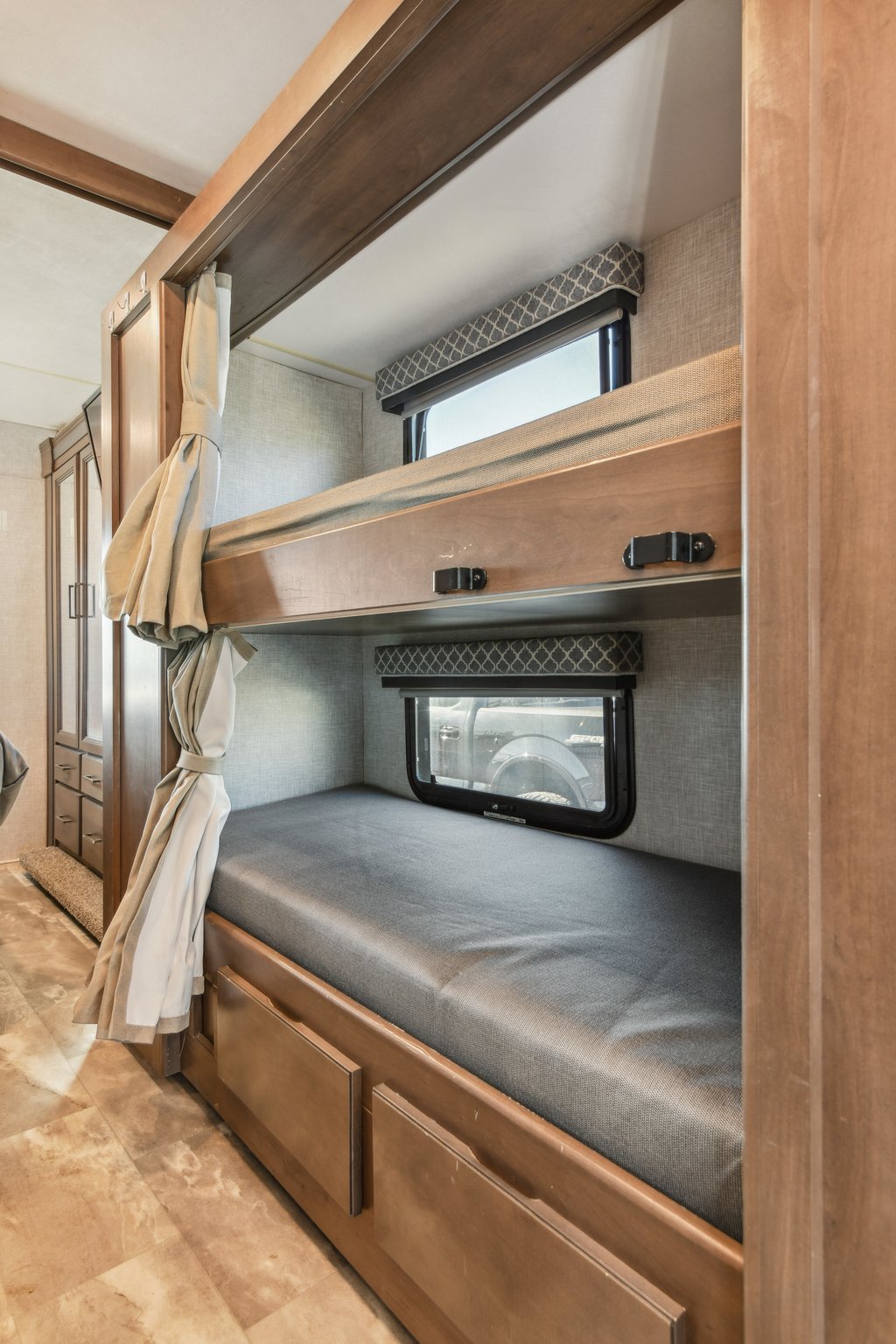 Inside this rv rental: cozy bunk beds with gray mattresses, individual windows, and privacy curtains, perfect for family travel.. Thor Motor Coach Quantum 2022
