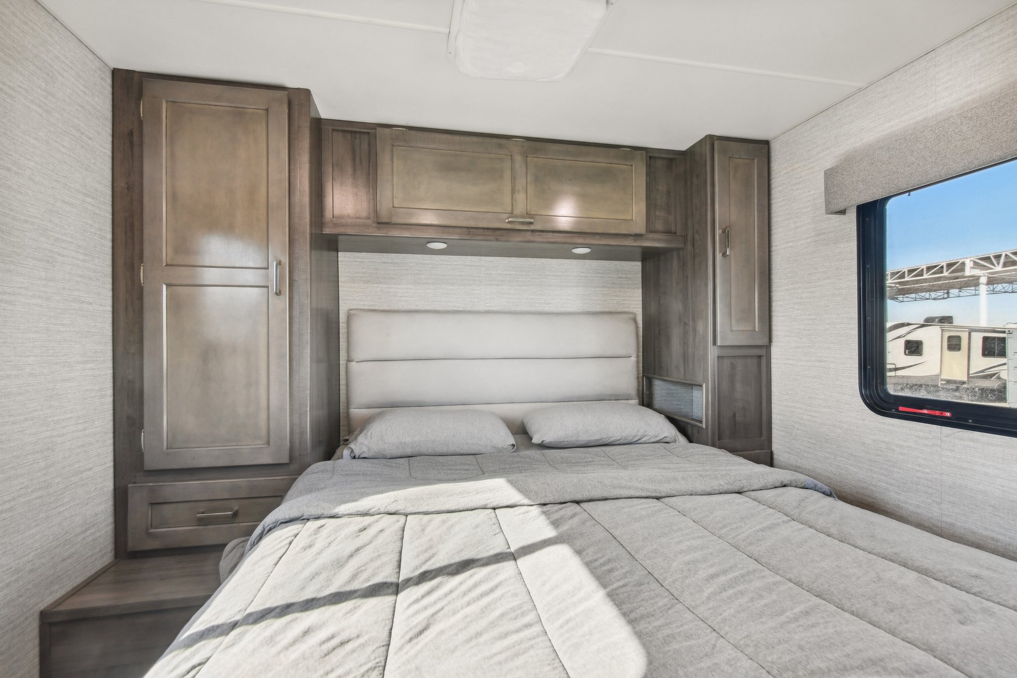 Cozy RV rental bedroom featuring a bed, ample built-in storage, and a window view, ideal for travel.. Winnebago Minnie Winnie 2020