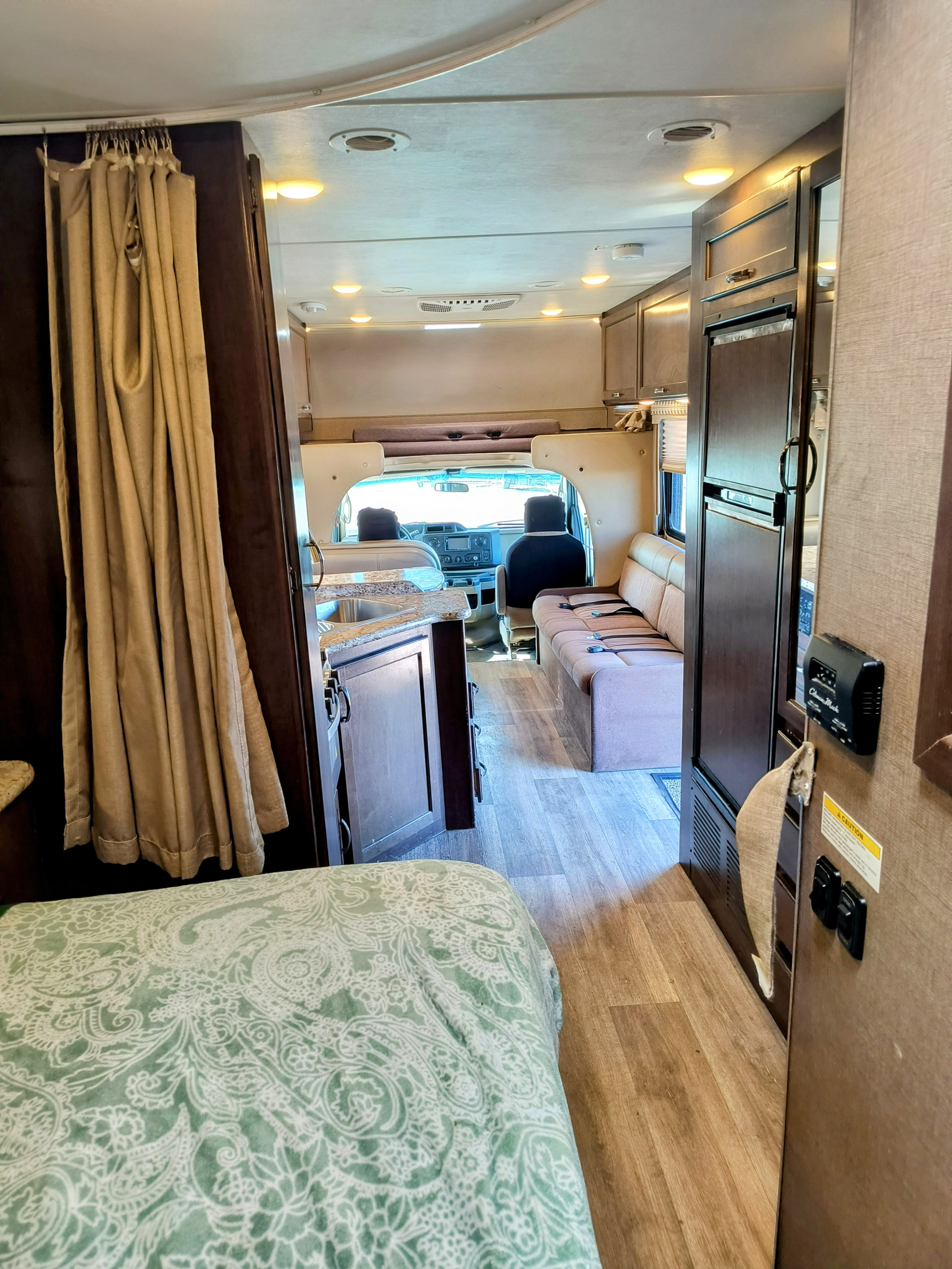 Interior view of an RV rental: bedroom in foreground, leading to kitchen, living area, and driver's cockpit.. Thor Motor Coach Four Winds 2017
