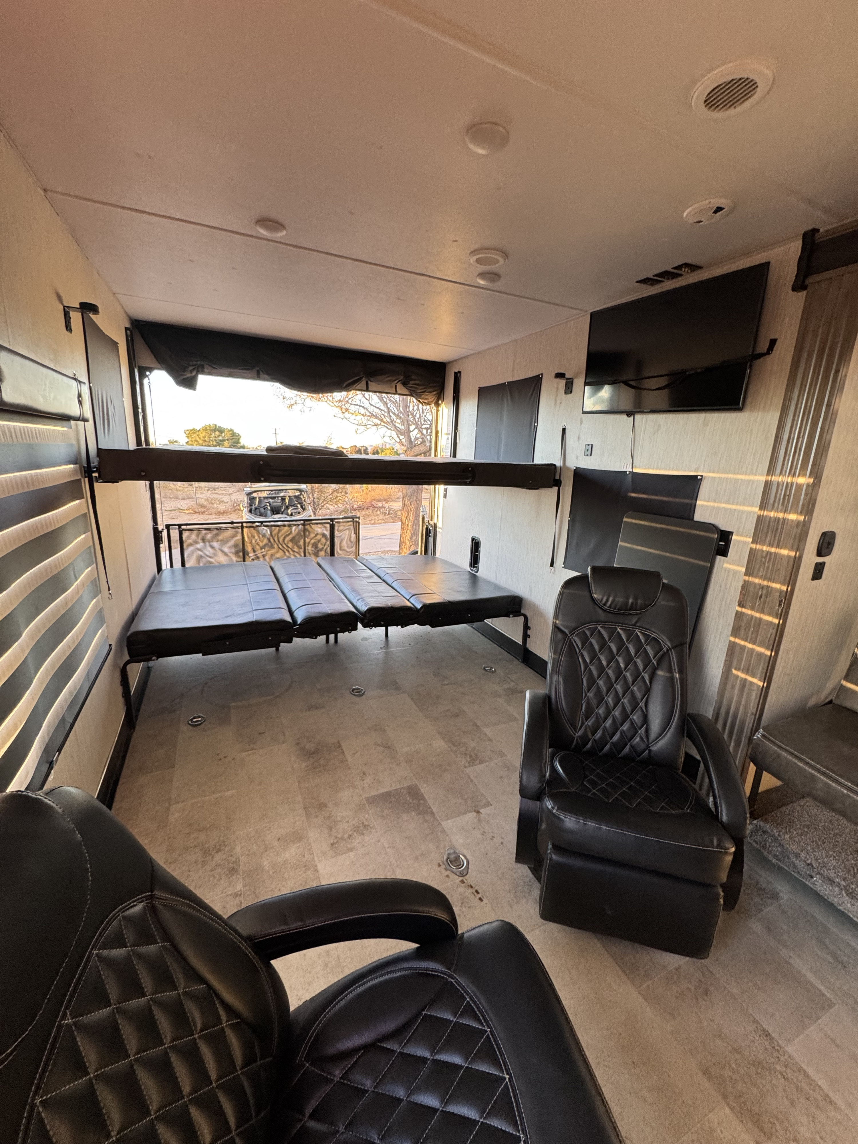 Spacious RV rental interior featuring convertible seating/beds, a large rear ramp door, comfy chairs, and a TV for ultimate comfort.. Forest River Vengeance 2020