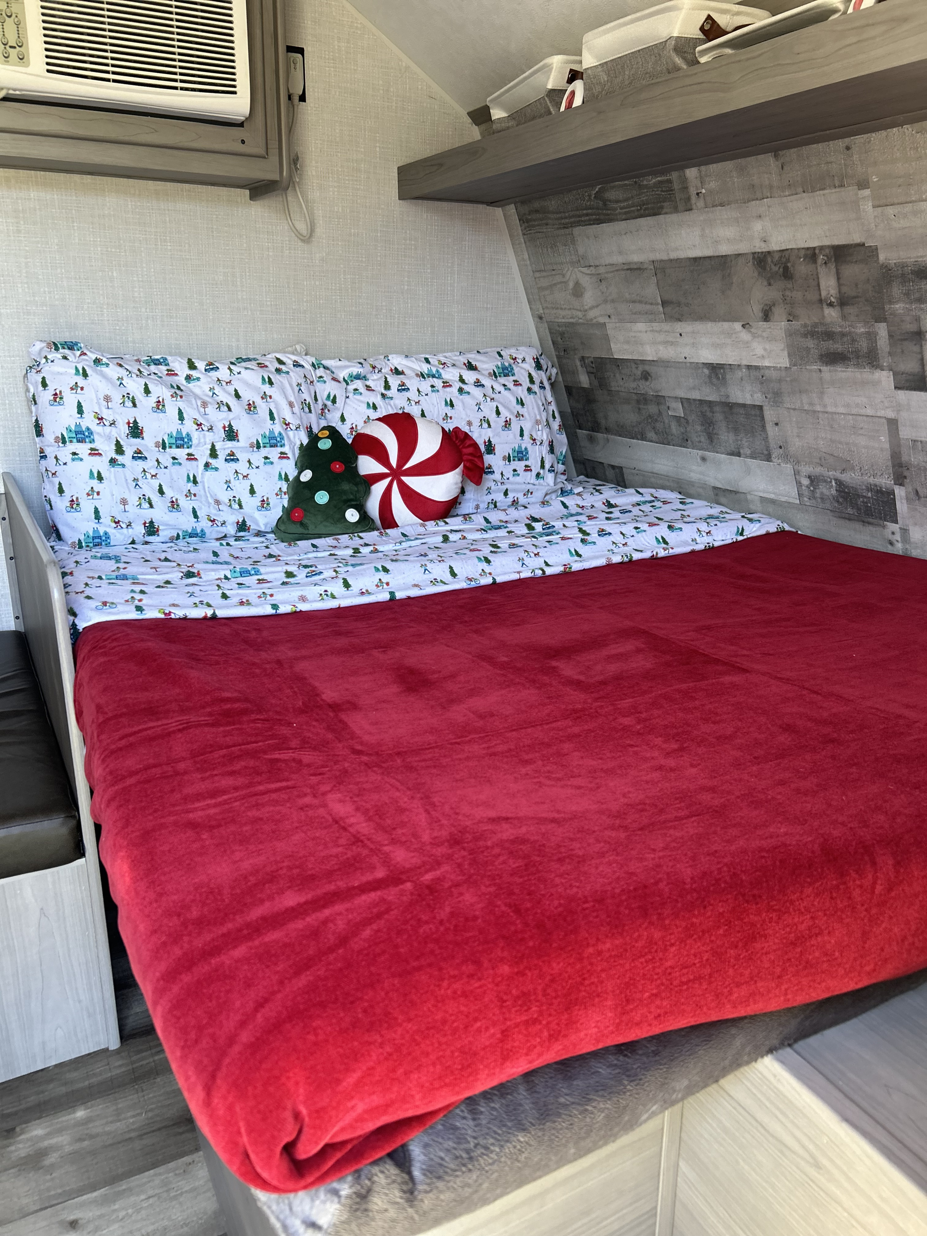 Cozy RV rental bedroom with festive holiday bedding, a vibrant red blanket, and ample storage.. Coleman Lantern LT 17B 2023