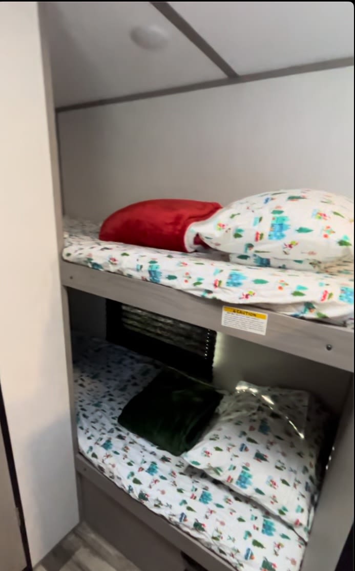 RV rental's cozy bunk beds featuring whimsical holiday bedding, offering a compact and comfortable sleeping area.. Coleman Lantern LT 17B 2023