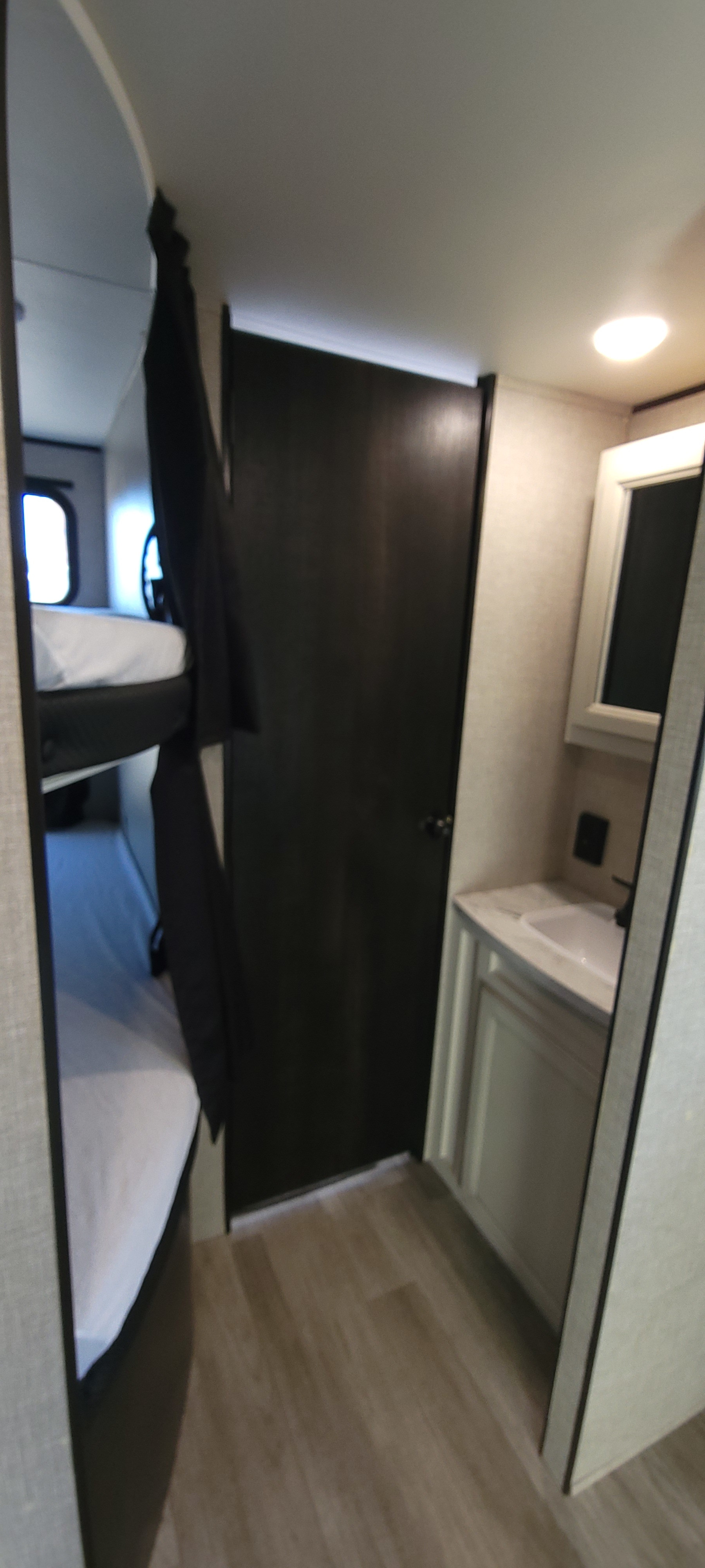RV rental interior showing bunk beds with privacy curtain, and a compact bathroom area with a sink and mirror.. Jayco Jay Flight Baja 2023