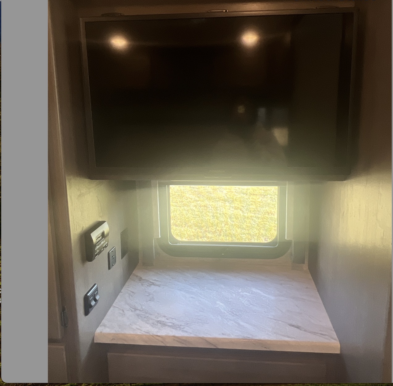Cozy **RV rental** living space: TV, window with outdoor view, countertop, and convenient wall controls.. Thor Motor Coach Traveler 2023