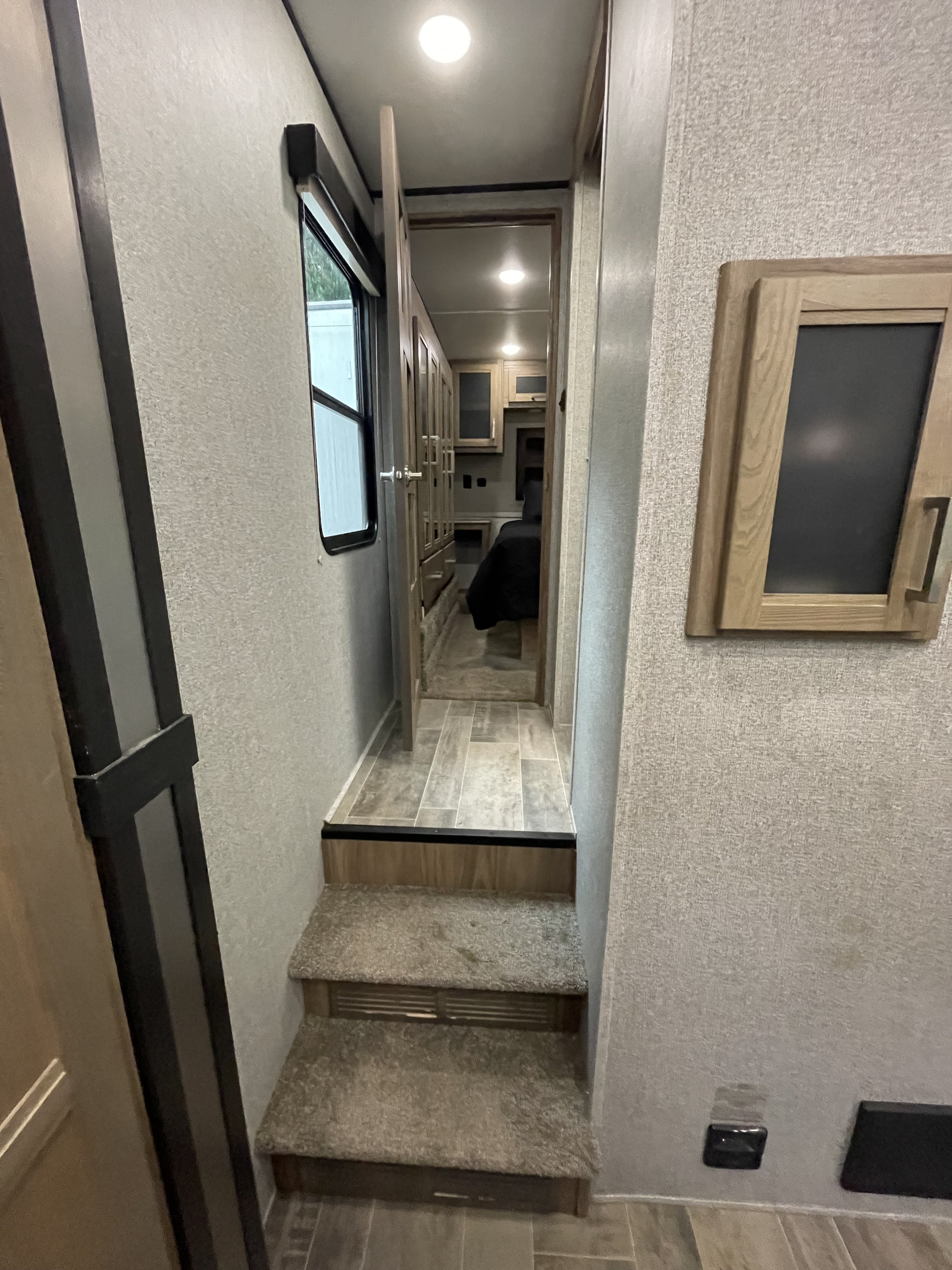 View of an RV rental's interior, featuring carpeted stairs leading to a hallway and bedroom area with cabinets.. Dutchmen 3586 2019