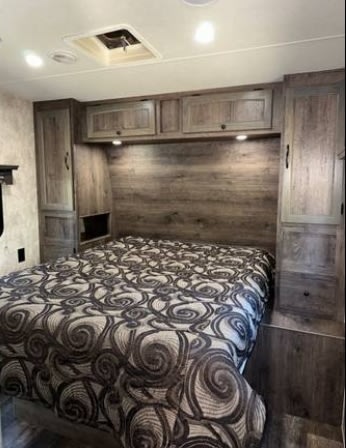 Cozy RV rental bedroom with a comfortable bed, patterned comforter, overhead cabinets, and built-in storage. Ideal for travel.. Eclipse Recreational Vehicles Attitude 2018