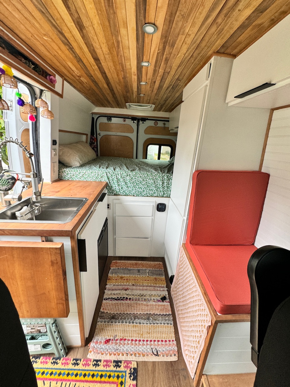 Step inside this cozy RV rental! Features a full kitchen, comfy bed, and seating area in a wood-paneled camper van.. Dodge Ram 1500 2020