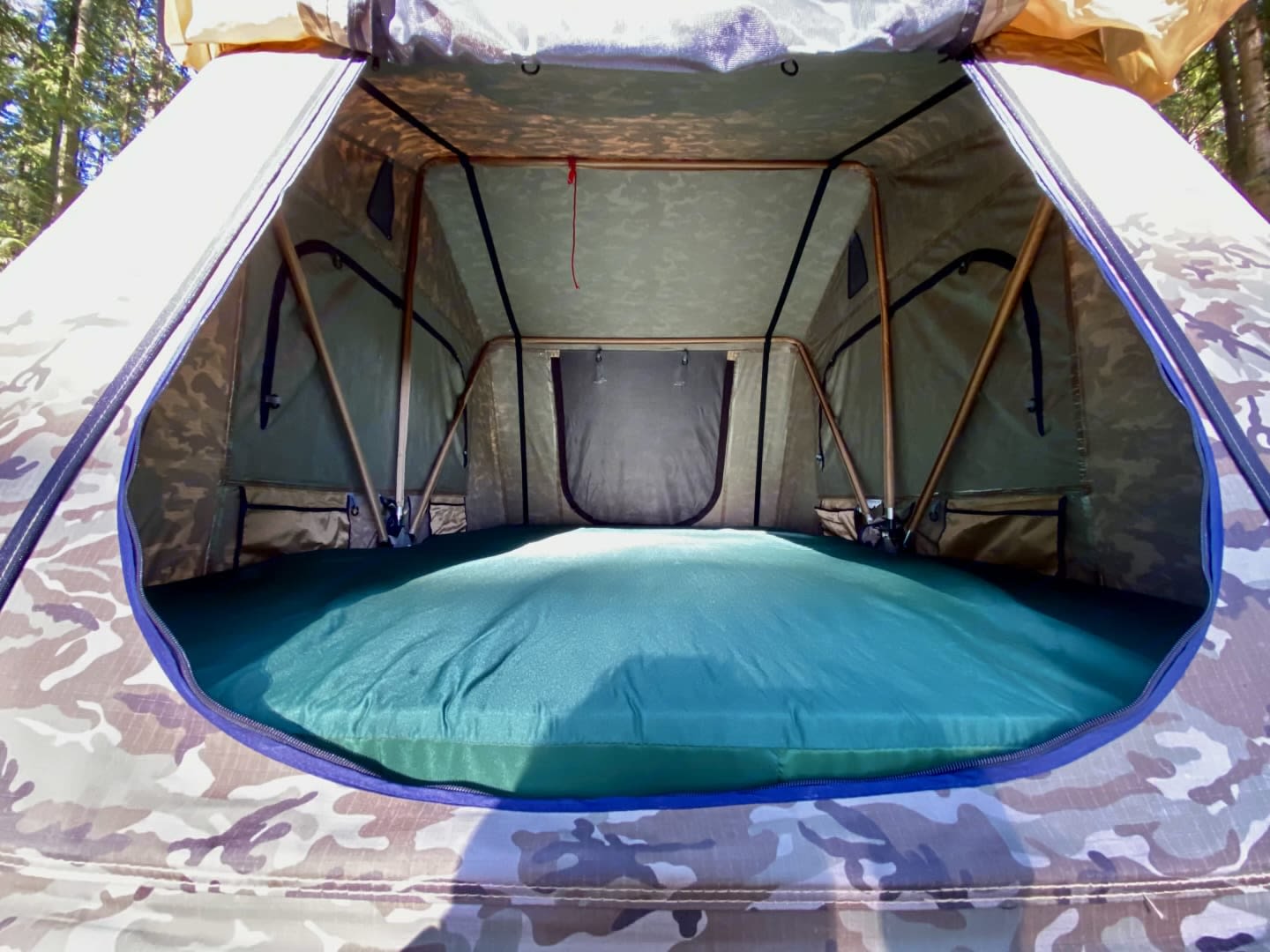 Comfortable sleeping area inside a camouflage rooftop tent, ideal for your RV rental adventure.. Frontier frontier 2006