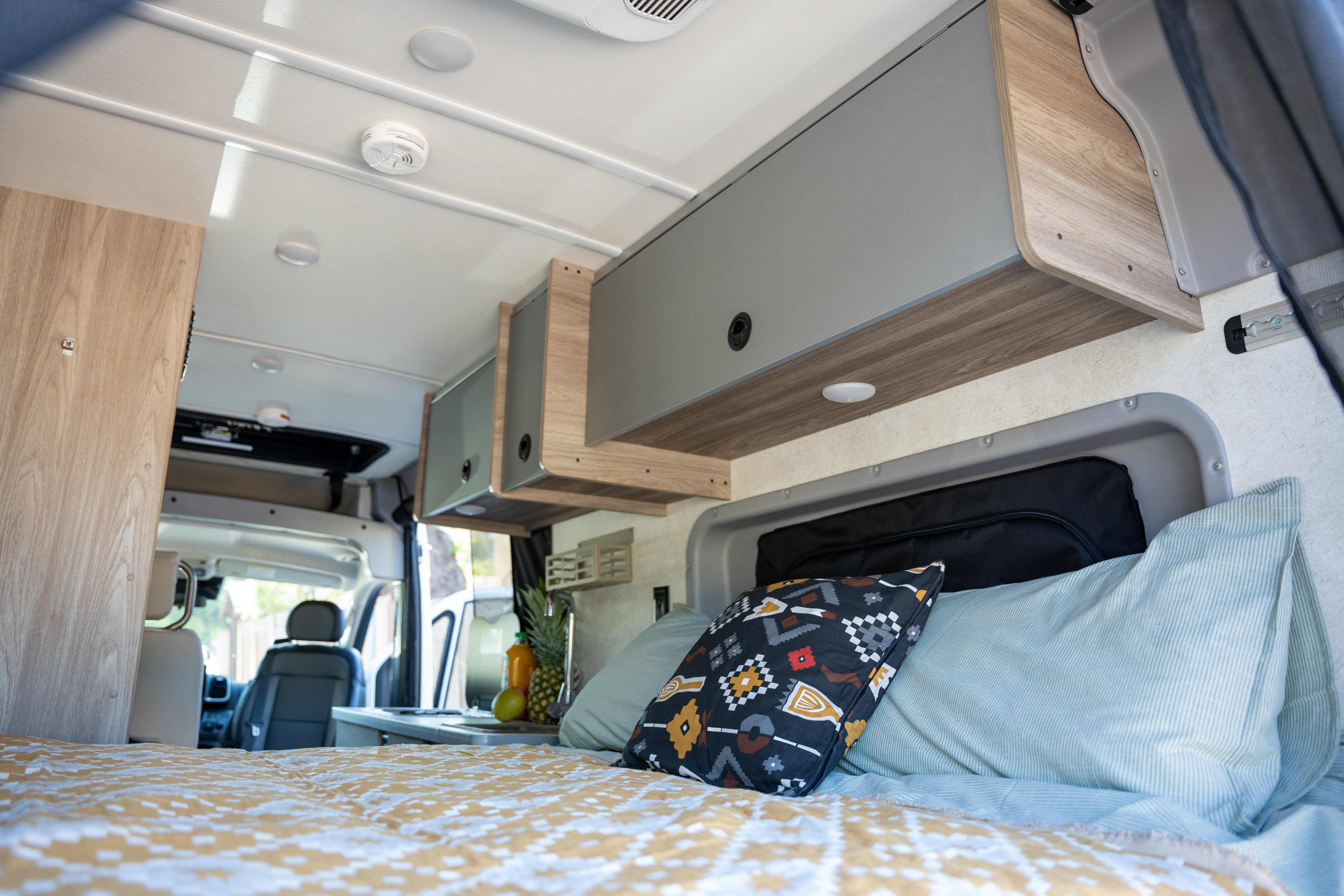 Step inside this cozy RV rental's interior, featuring a comfortable bed, overhead cabinets, and a compact kitchen.. Winnebago Solis 59px 2025