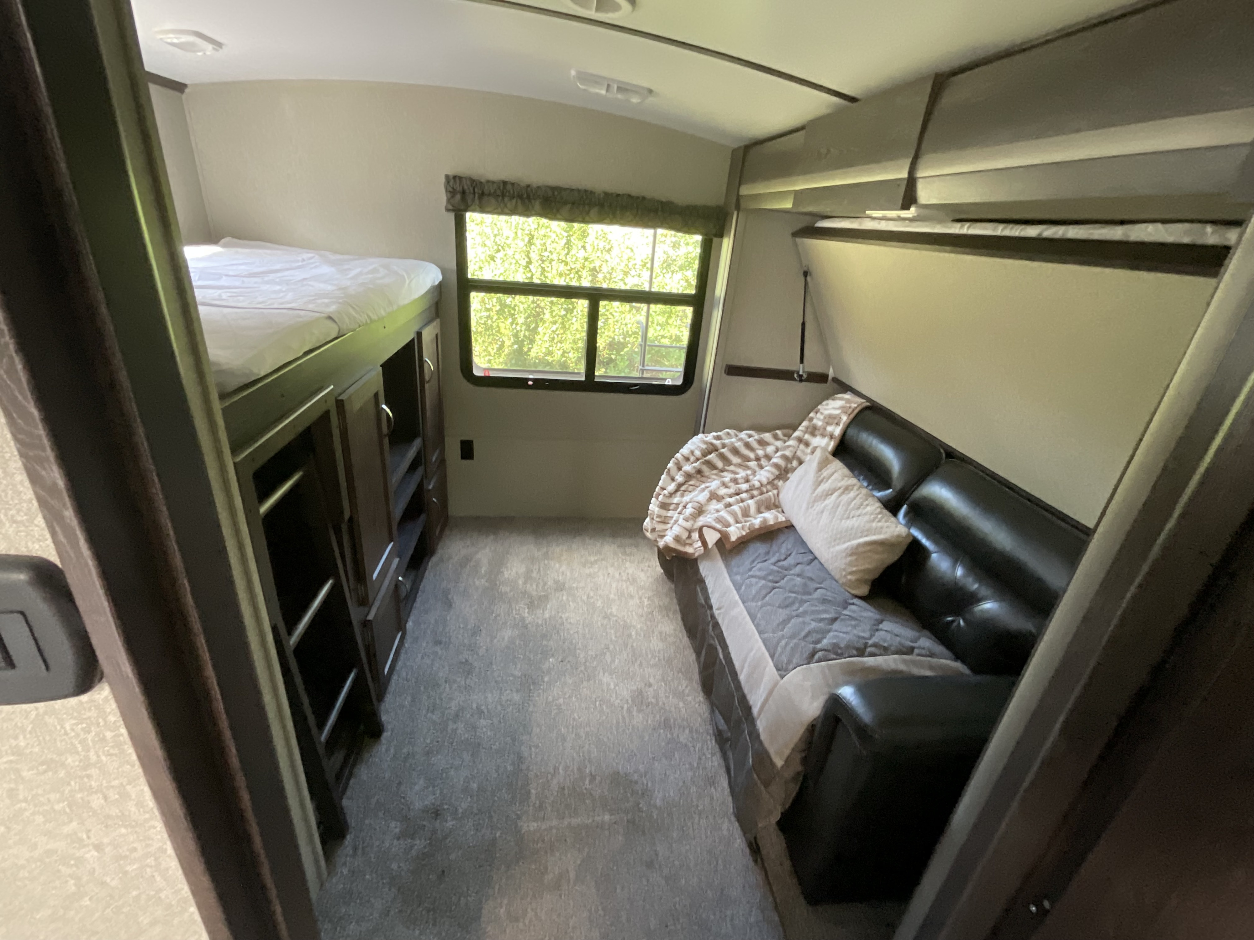 RV rental interior: bunk beds, sofa, and bright window. A cozy, compact sleeping and living space for travelers.. Keystone RV Outback Super-Lite 2018