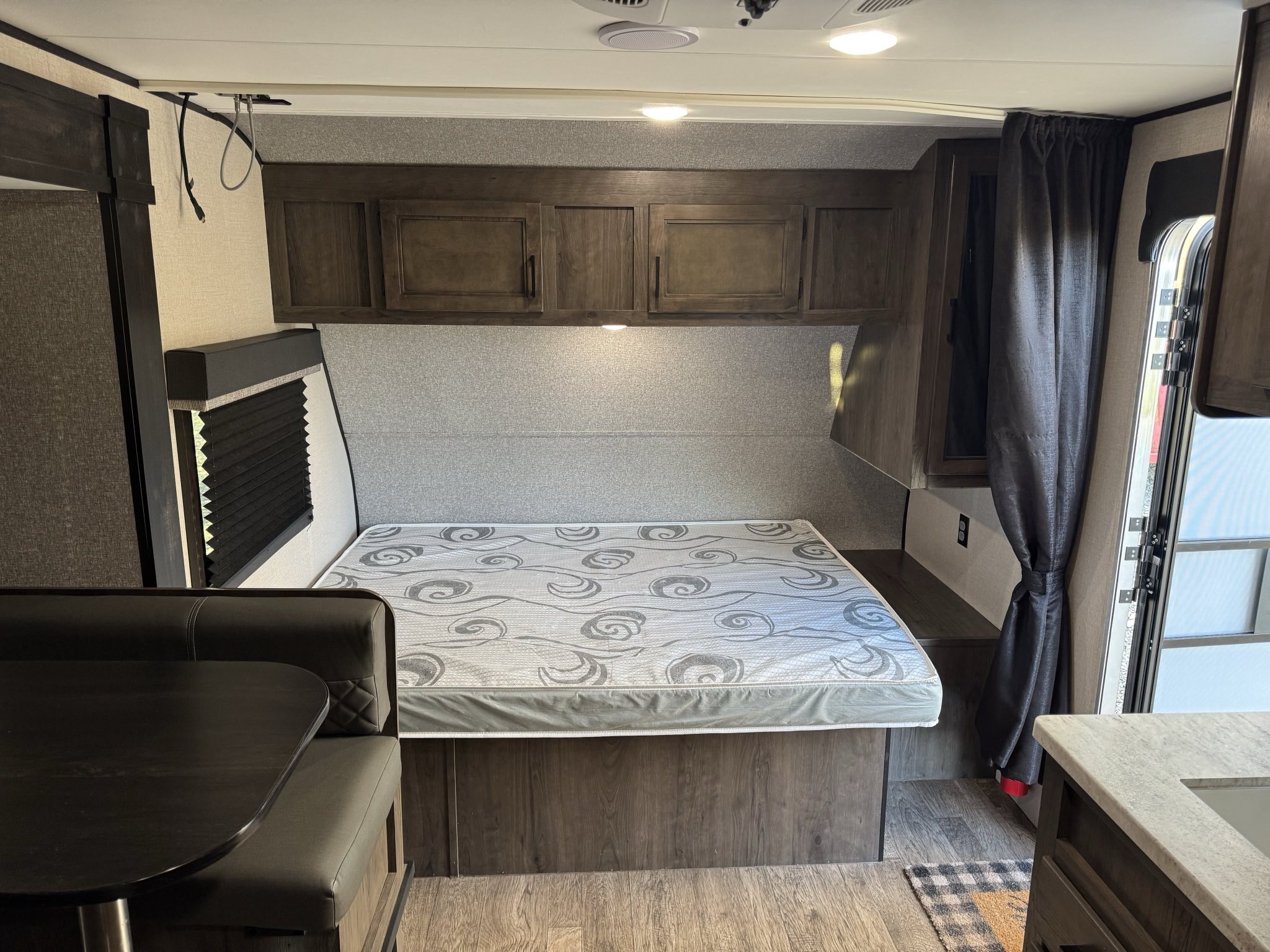 View inside a modern RV rental, featuring a comfortable bed, compact dinette, and small kitchen area.. Starcraft Autumn Ridge 2022